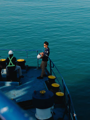 Two men on a boat deck overlooking the ocean.
