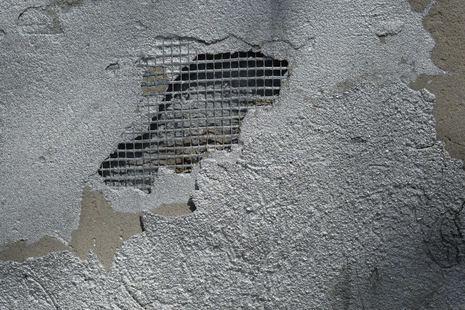 Damaged concrete wall with exposed metal mesh during renovation