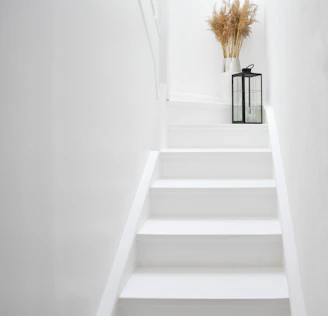 White staircase with a lantern and dried flowers