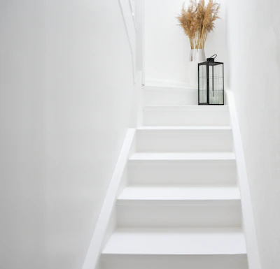 White staircase with a lantern and dried flowers