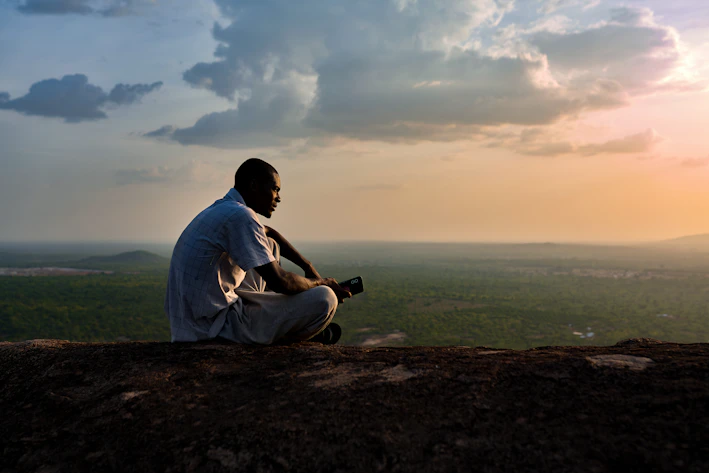 Man sitting on a cliff at sunset