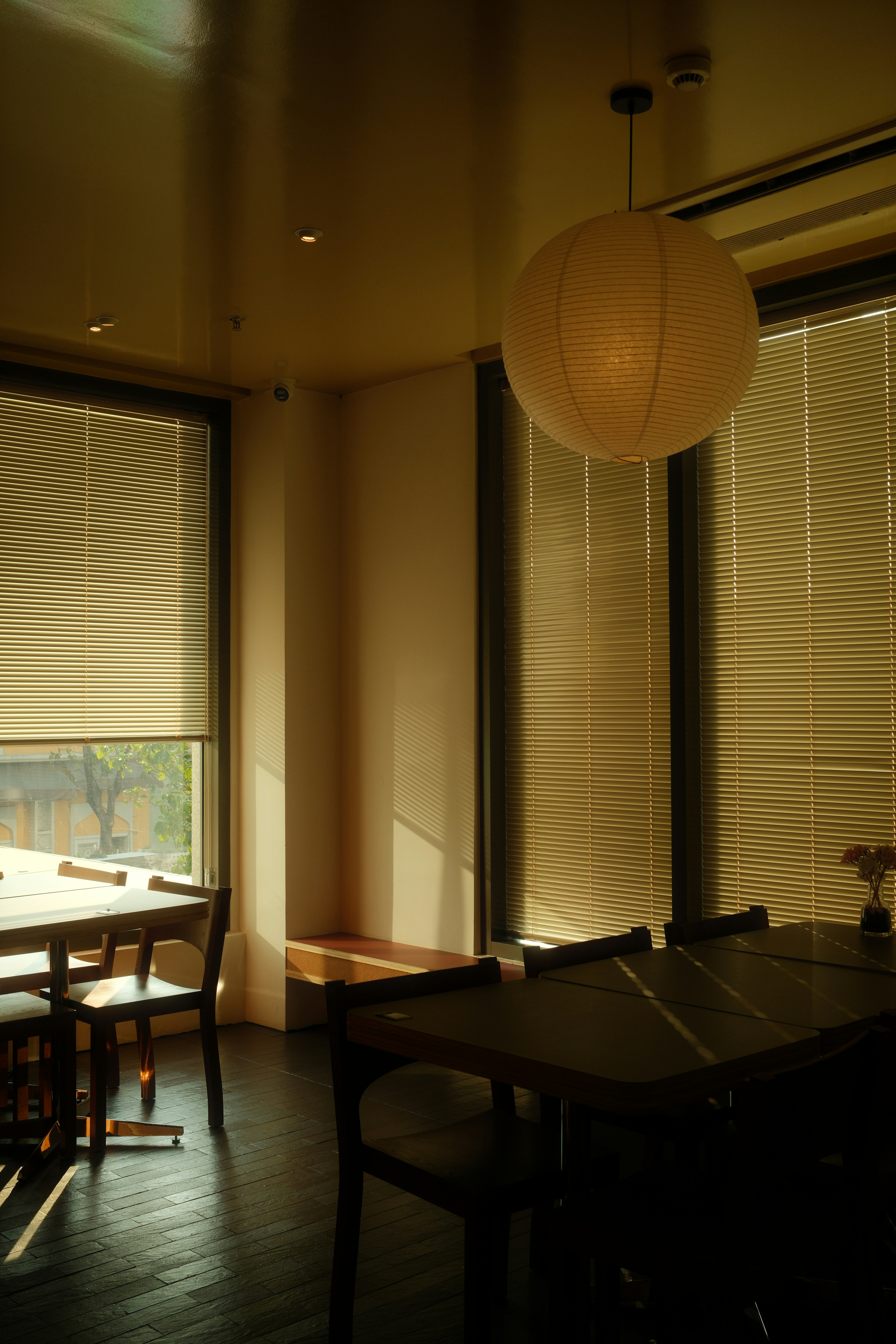 Sunlight streams through blinds onto dining tables.