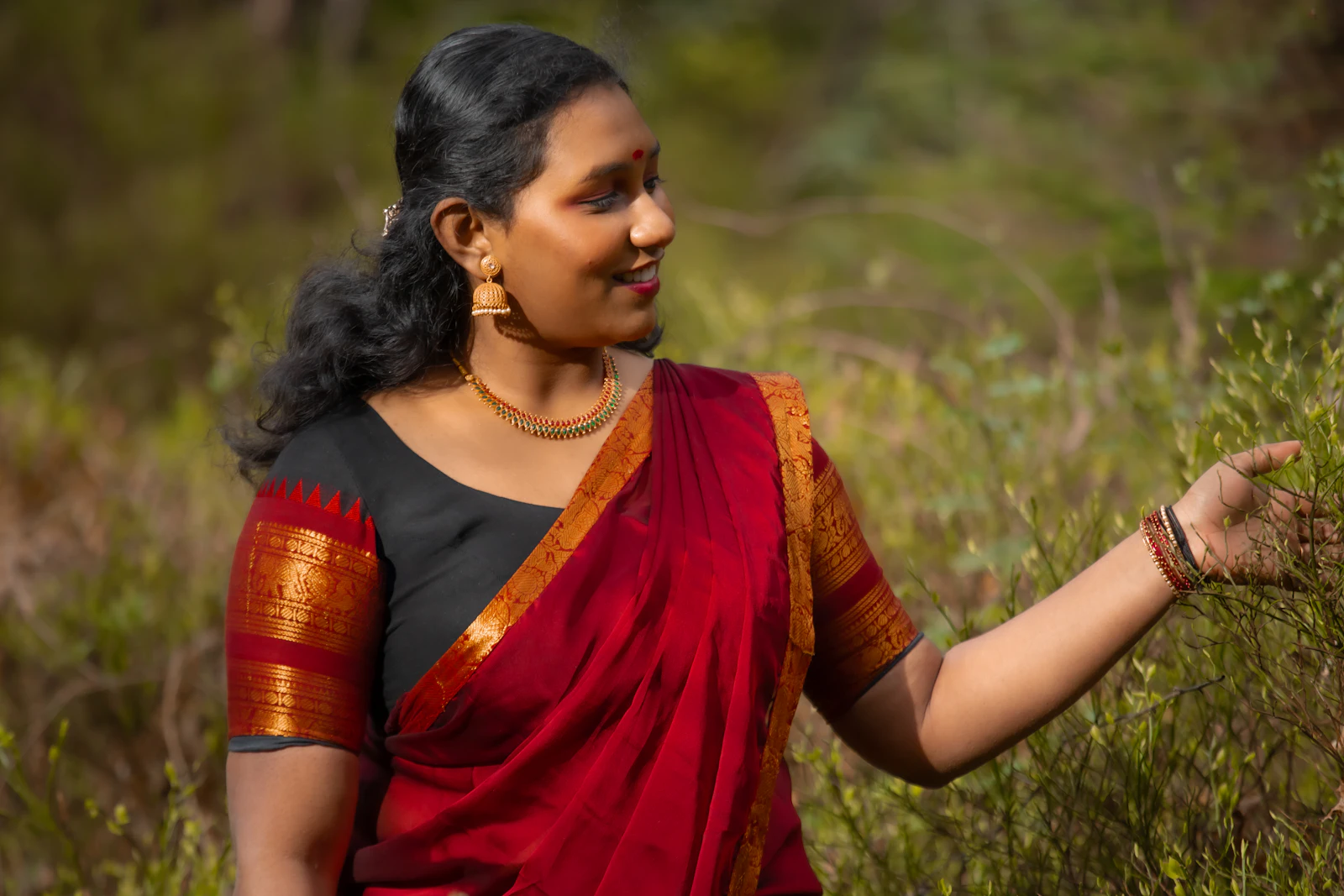 Kavita Bisht, companionship caregiver, in a red sari tending a plant outdoors