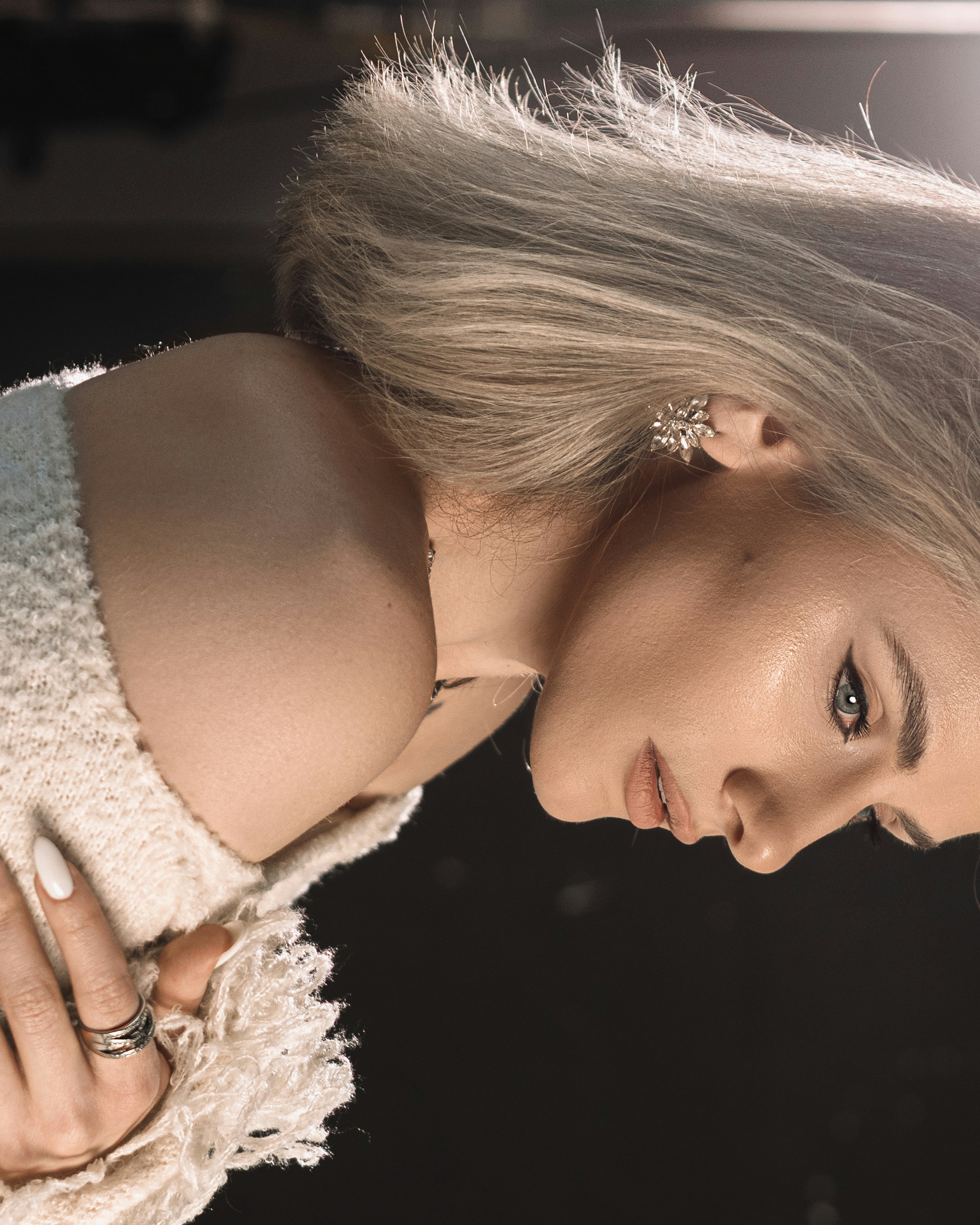 A woman with blonde hair wearing a white textured top.