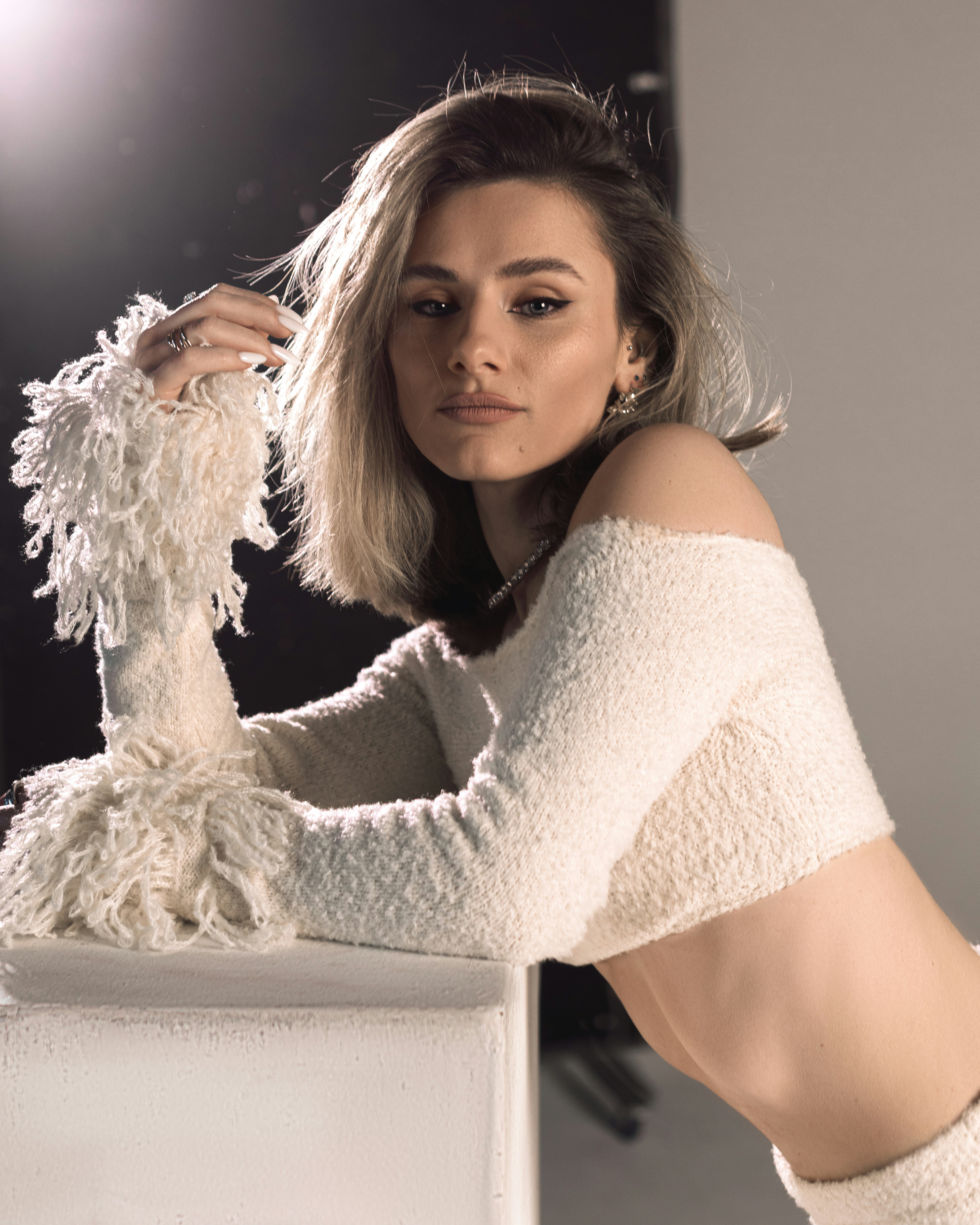 A young woman with blonde hair wearing a white sweater