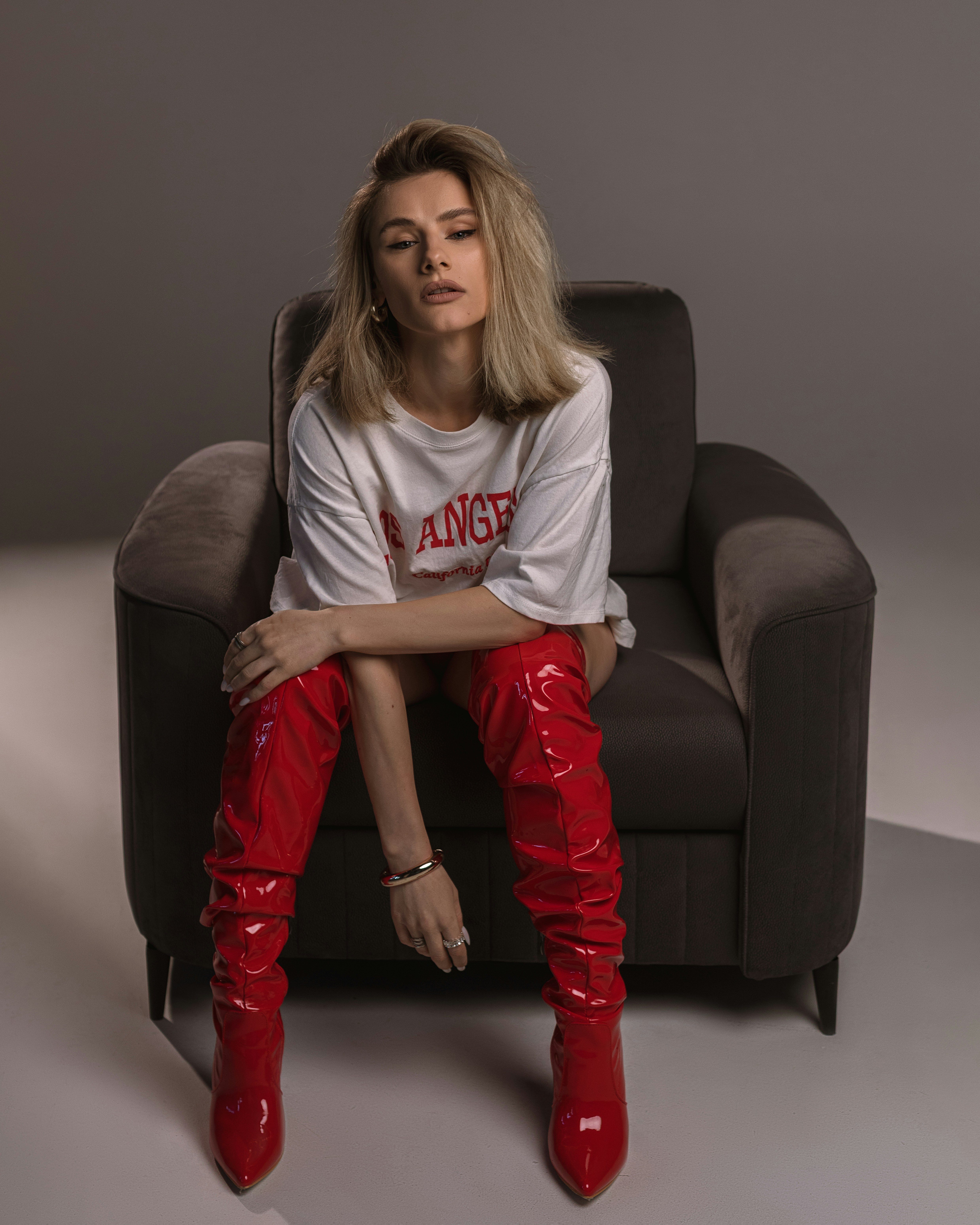 A woman in red boots sits in a chair.