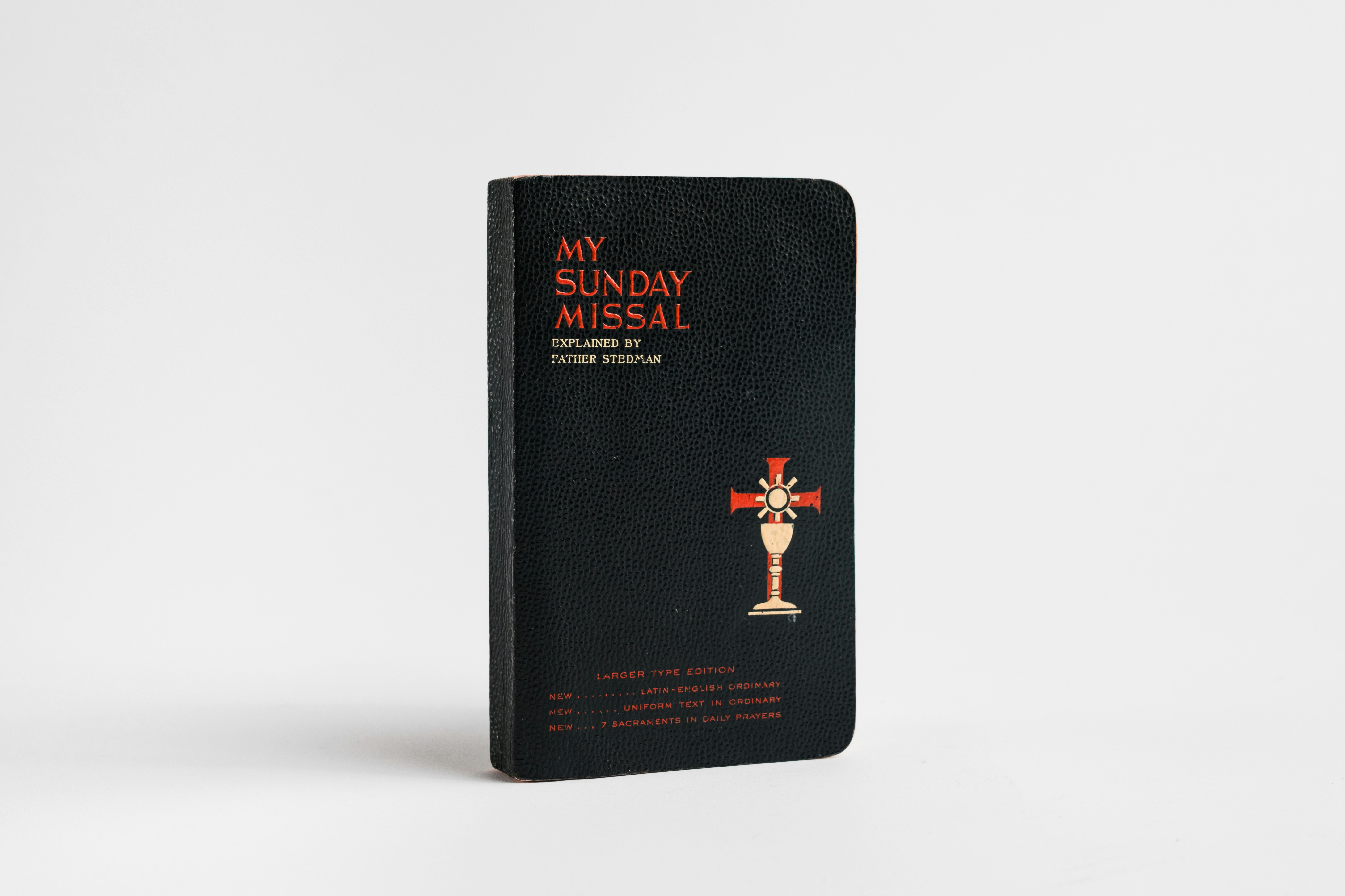 Un libro negro con texto rojo y un símbolo de cáliz