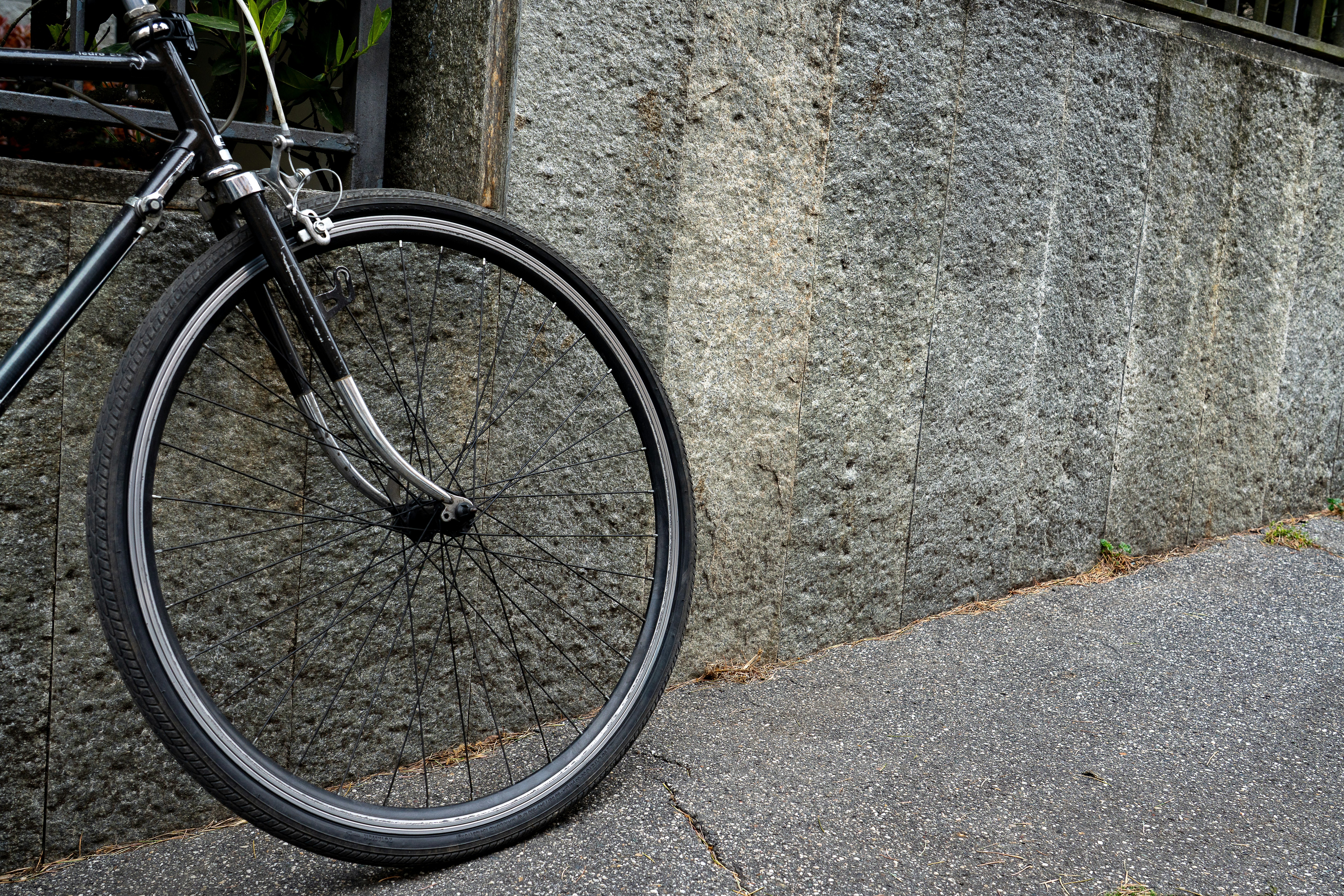 Una bicicleta se apoya contra una pared de piedra texturizada.