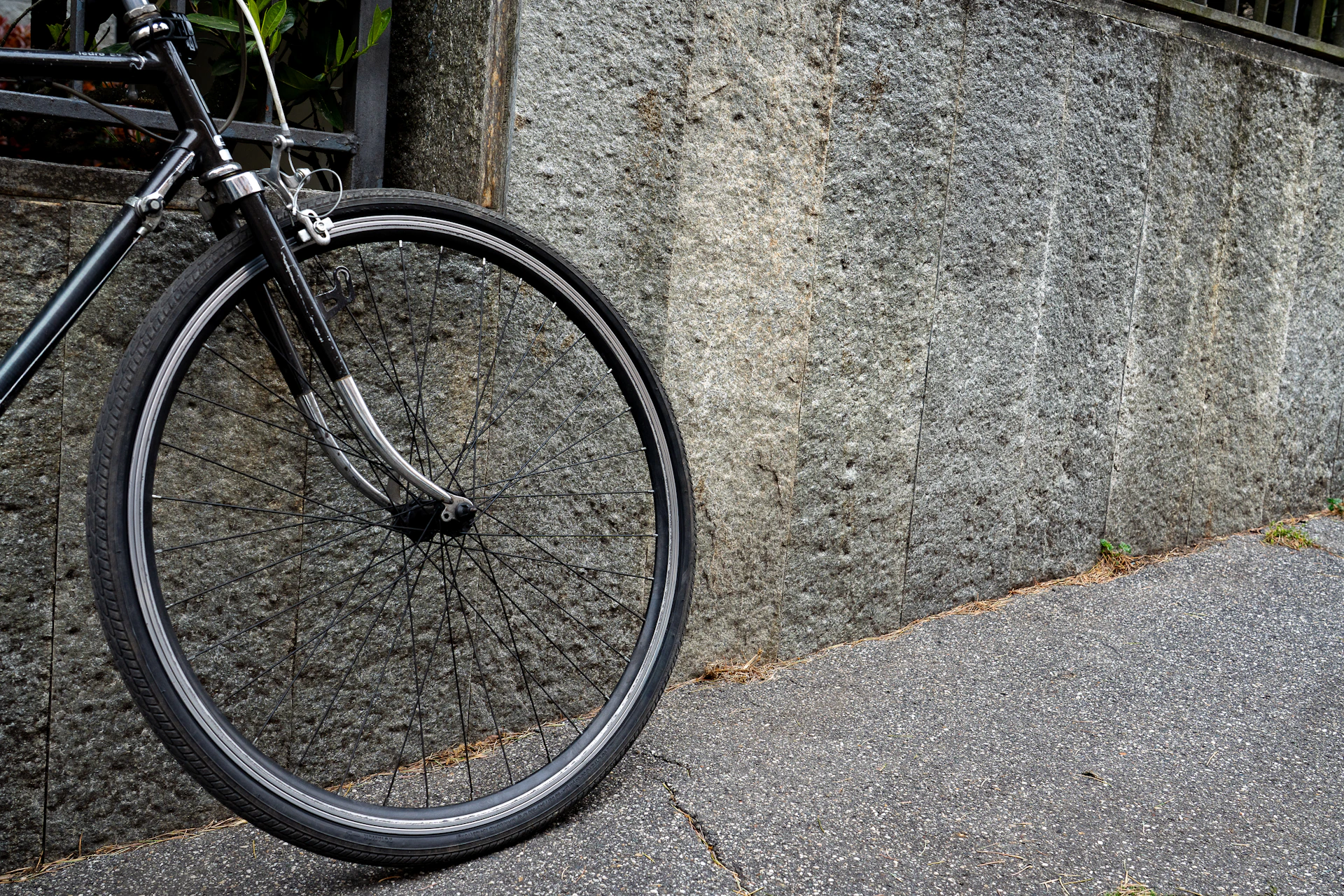 A bicycle leans against a textured stone wall.