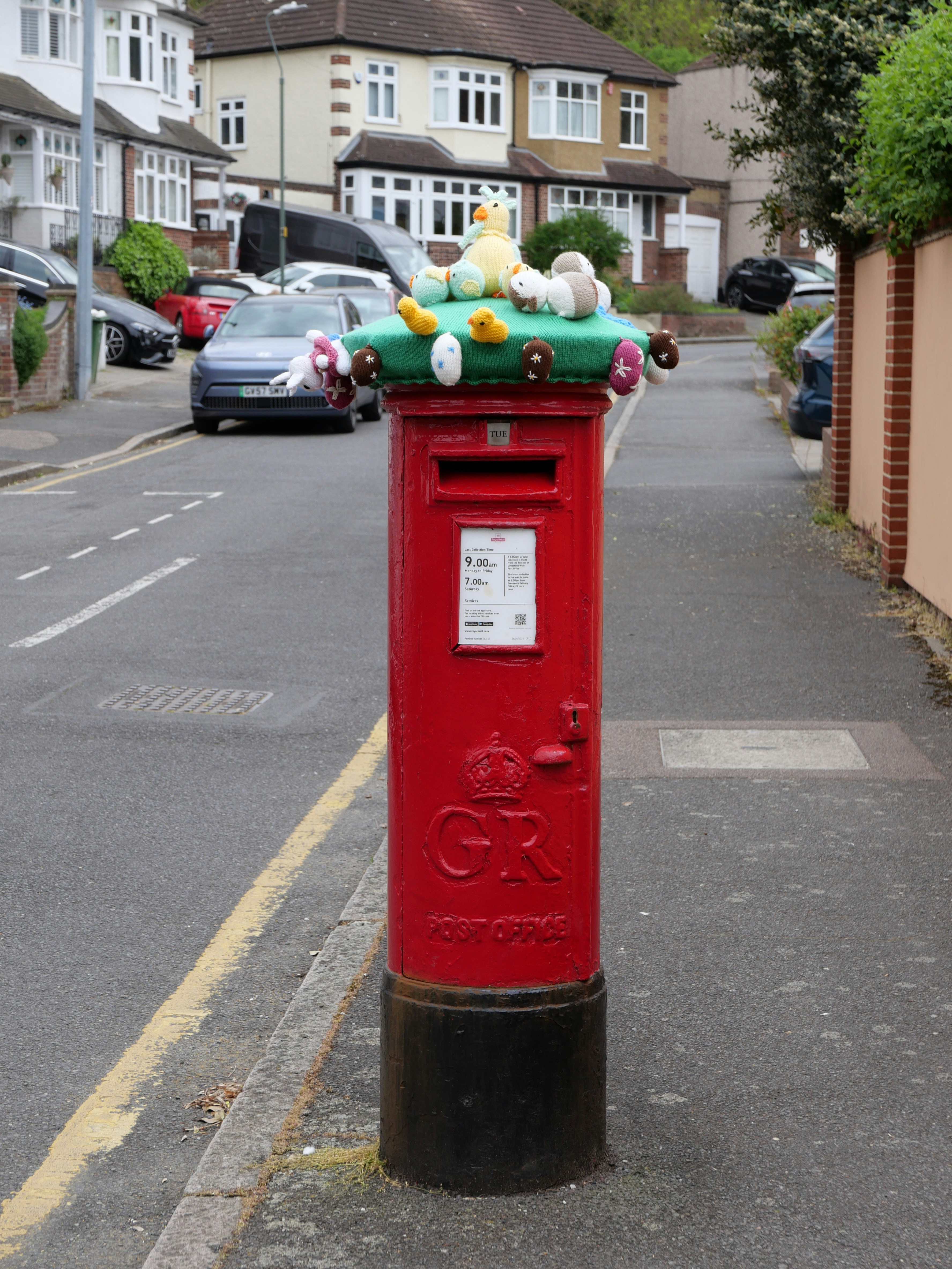 Red post box decorated with easter eggs and chicks
