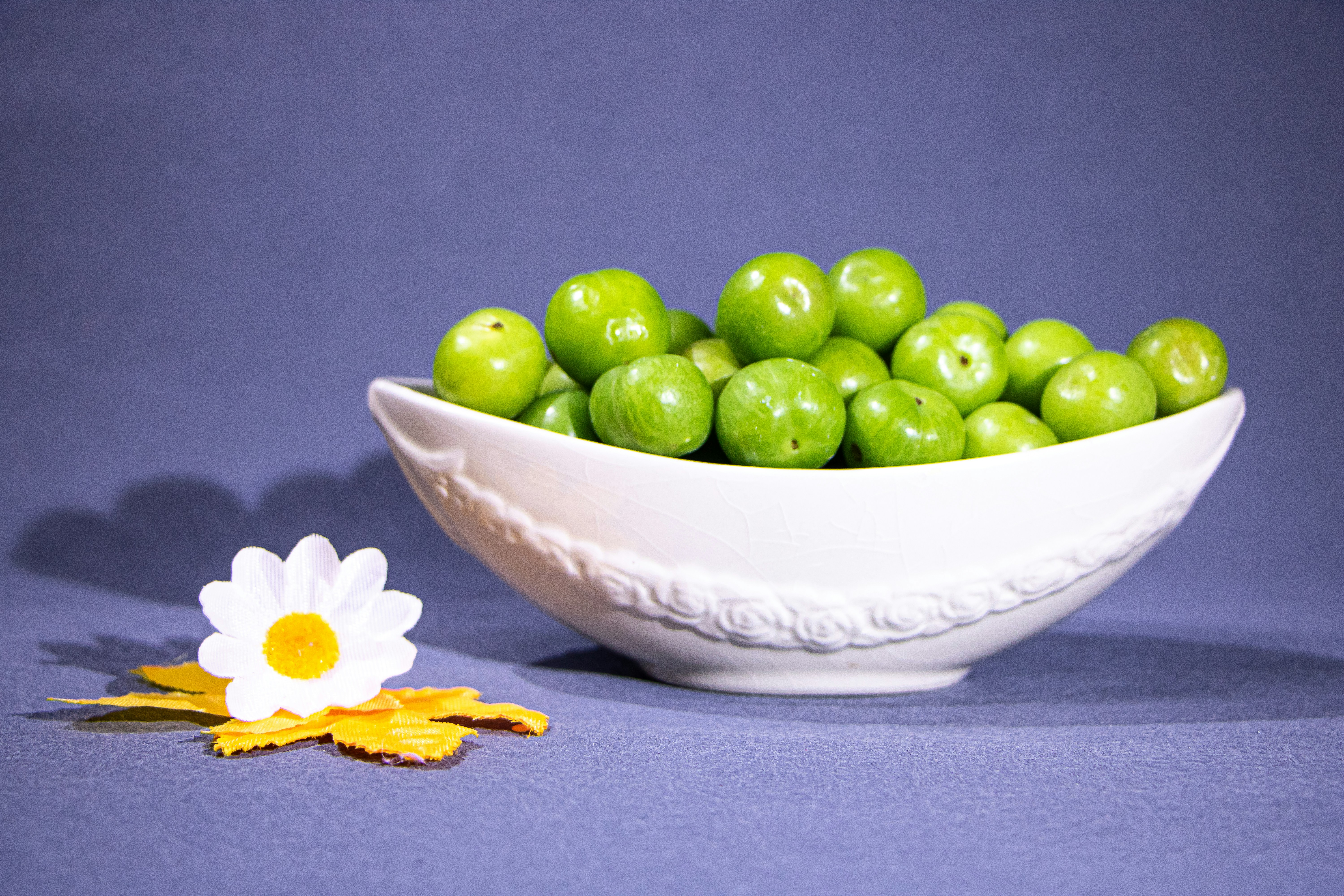 Bowl of green plums with a daisy