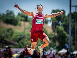 Athlete in mid-air during a long jump competition.