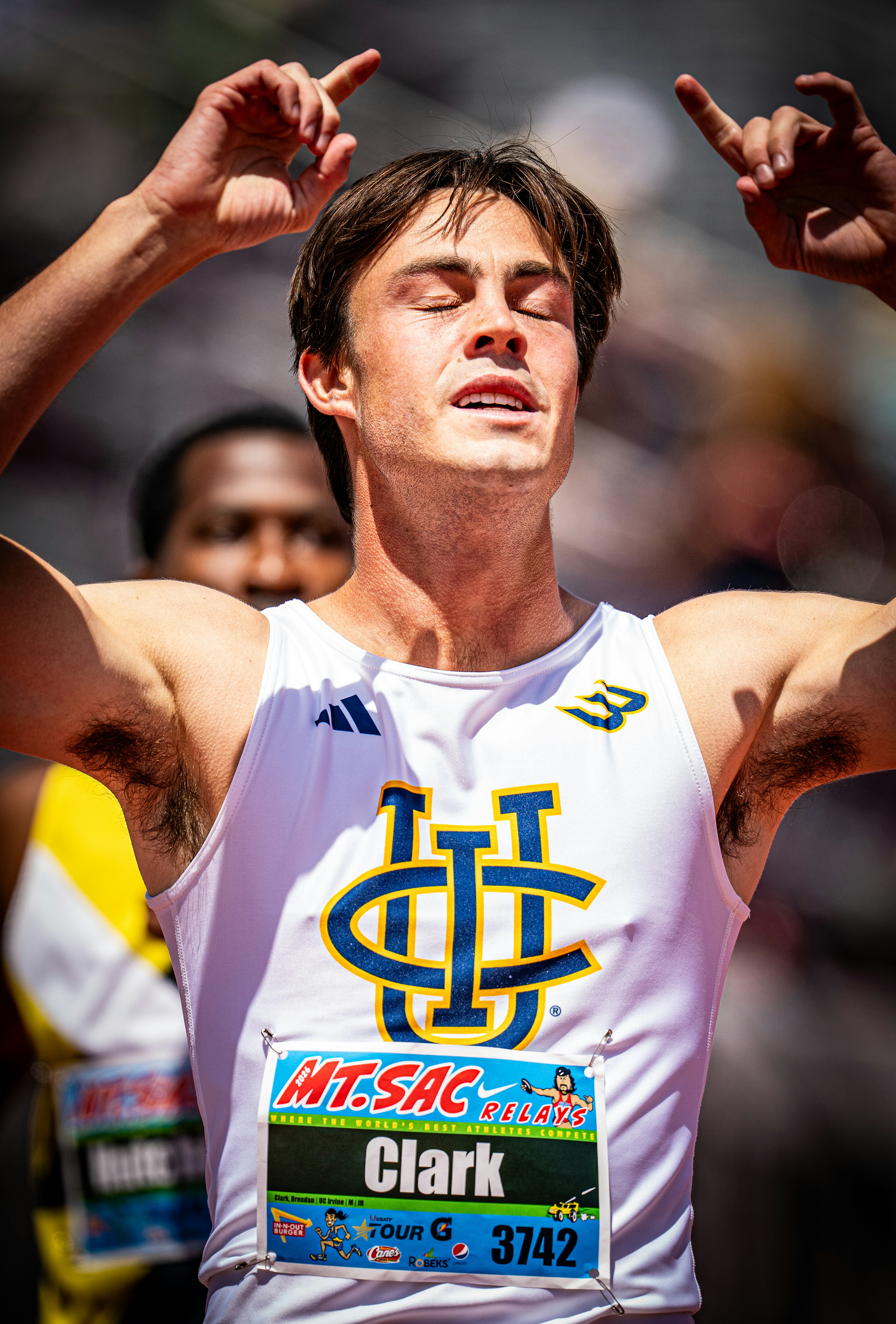 A male runner celebrates a victory with arms raised