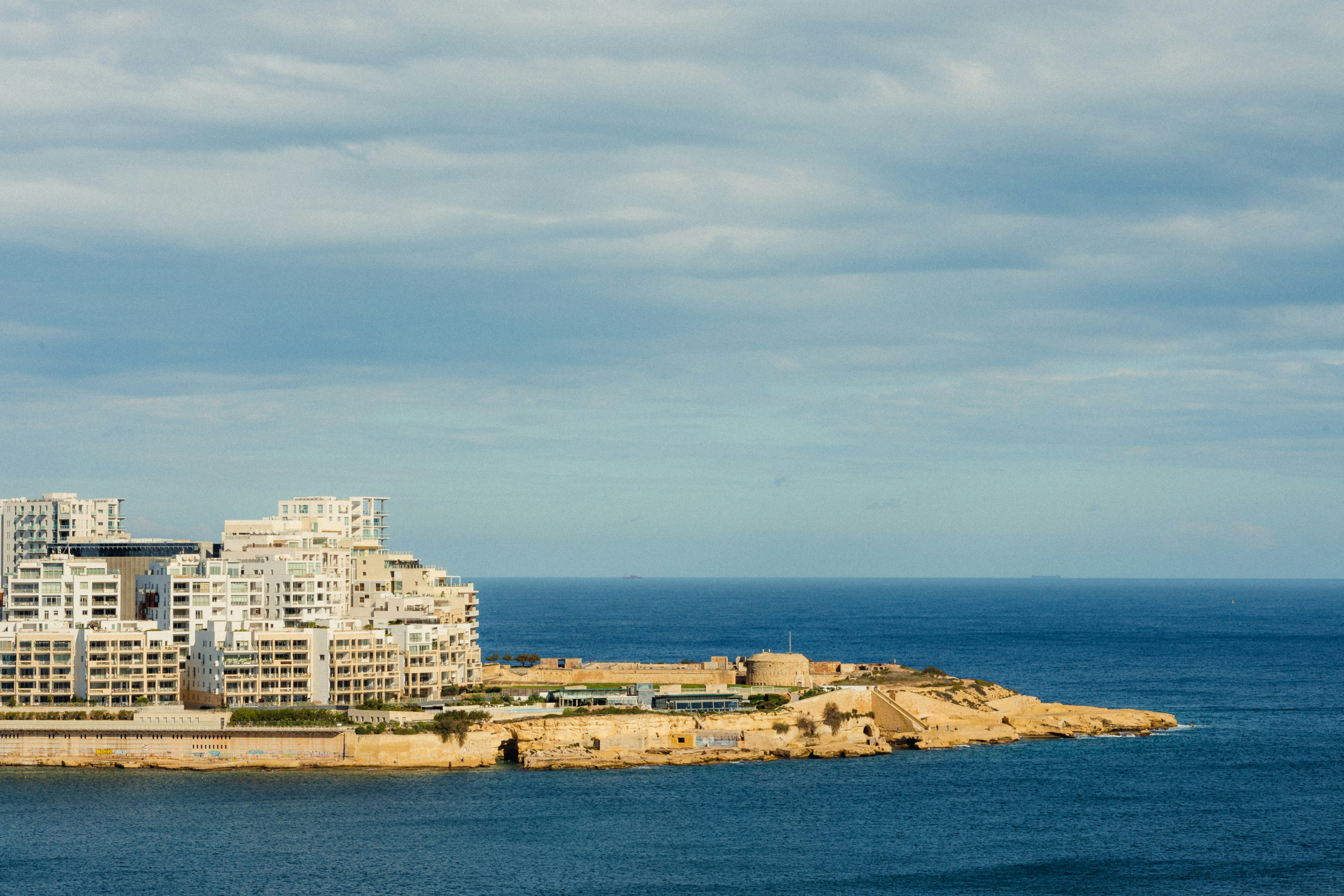 Modern buildings on a coastal peninsula overlooking the sea.