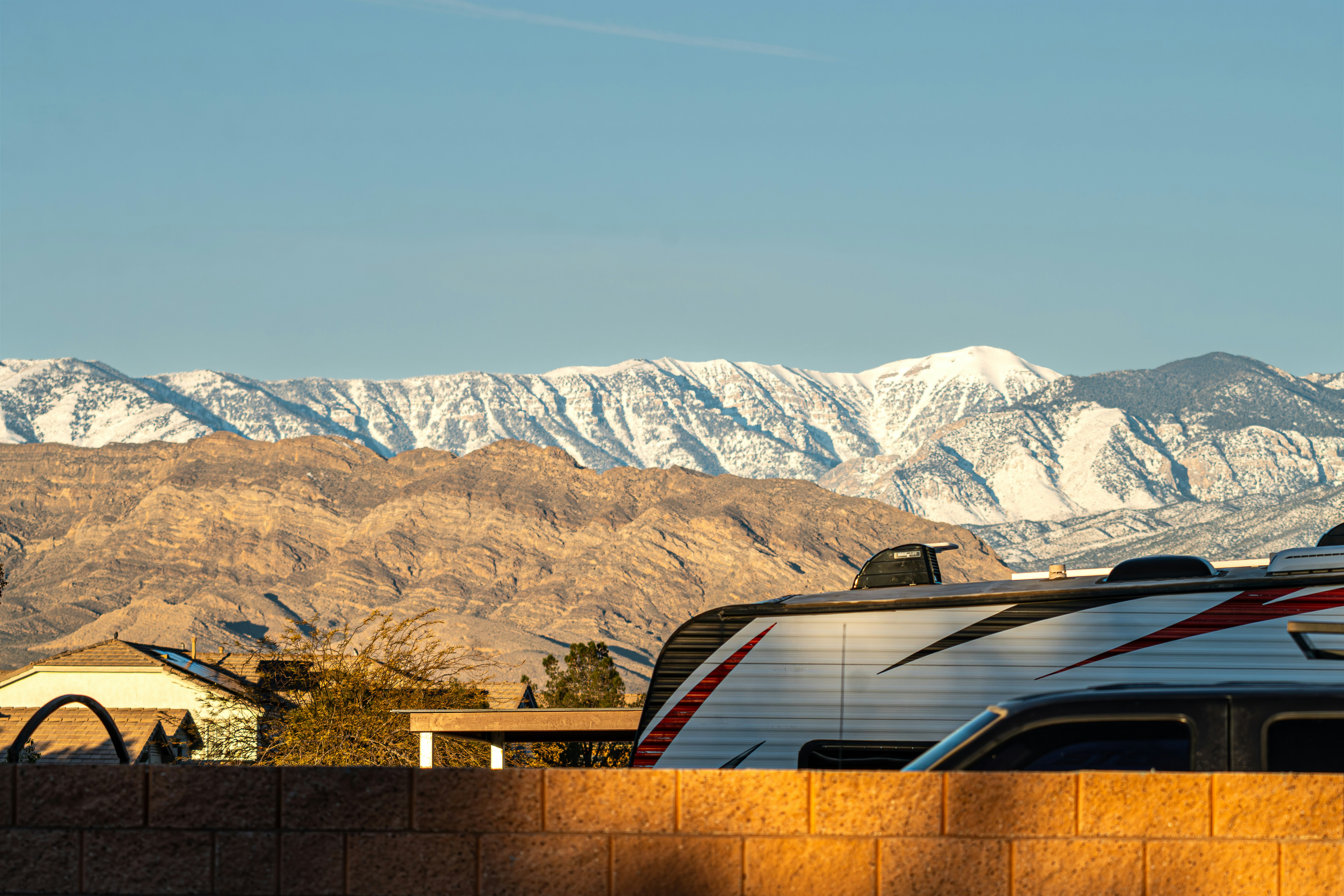 Snow-capped mountains behind a residential area and rv.