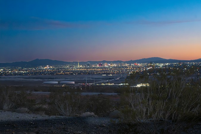 Las Vegas city lights glowing under a soft twilight sky with mountains on the horizon, the kind of early light guests will see at the 7:30 a.m. Sunrise Remembrance