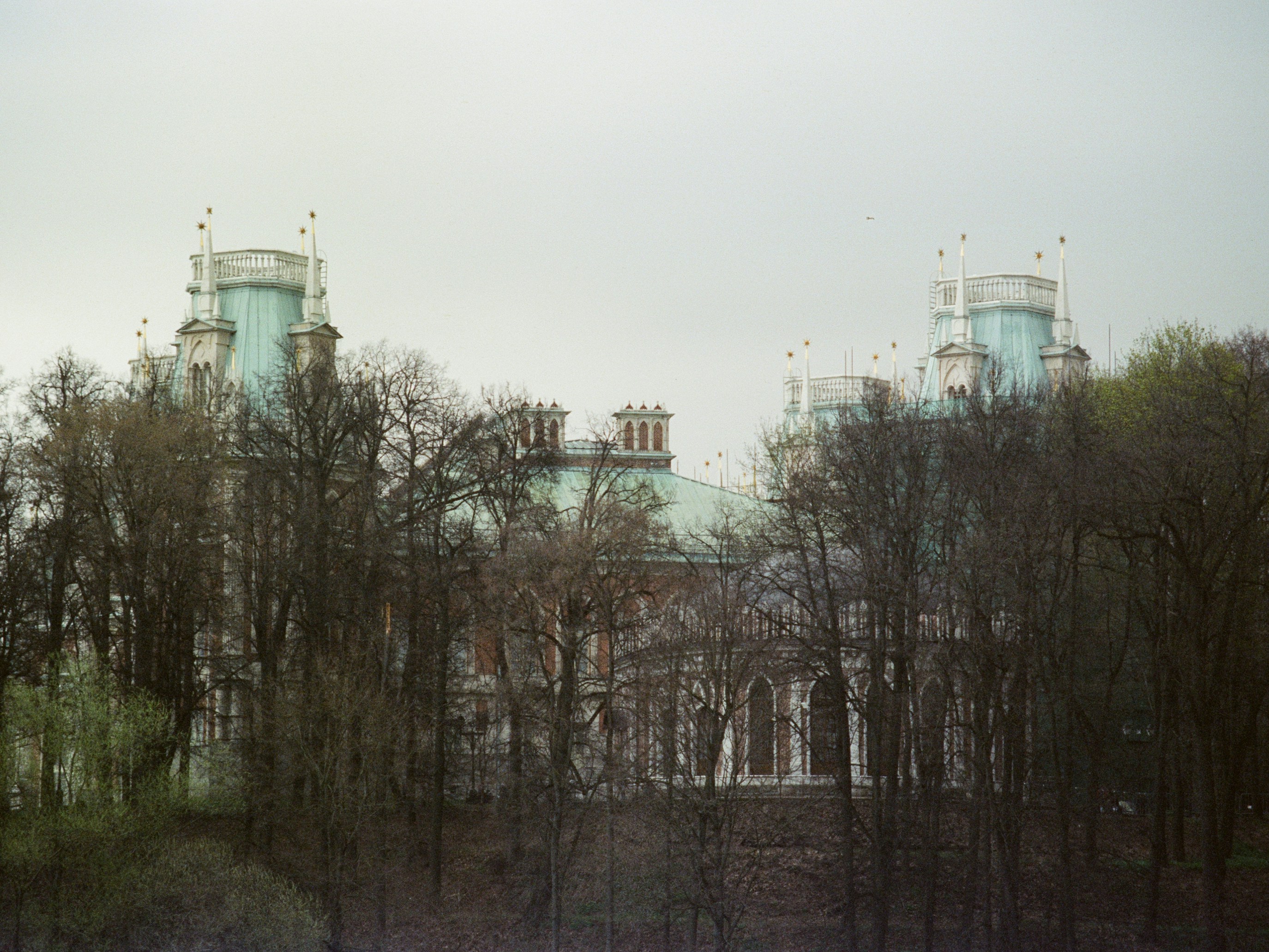 A grand building with turrets behind bare trees