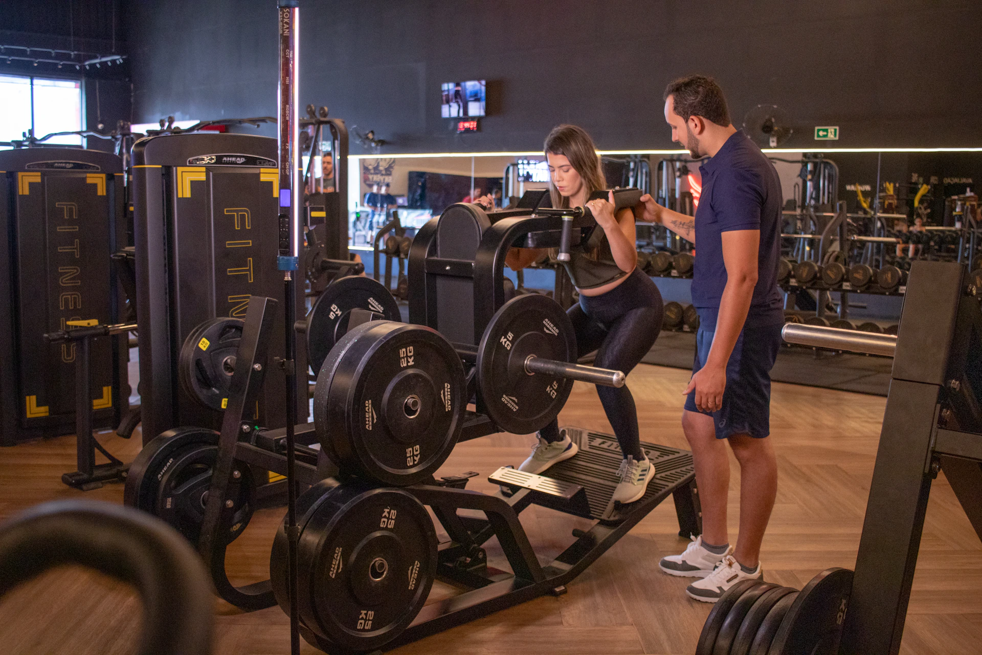 Woman lifting weights with trainer in gym