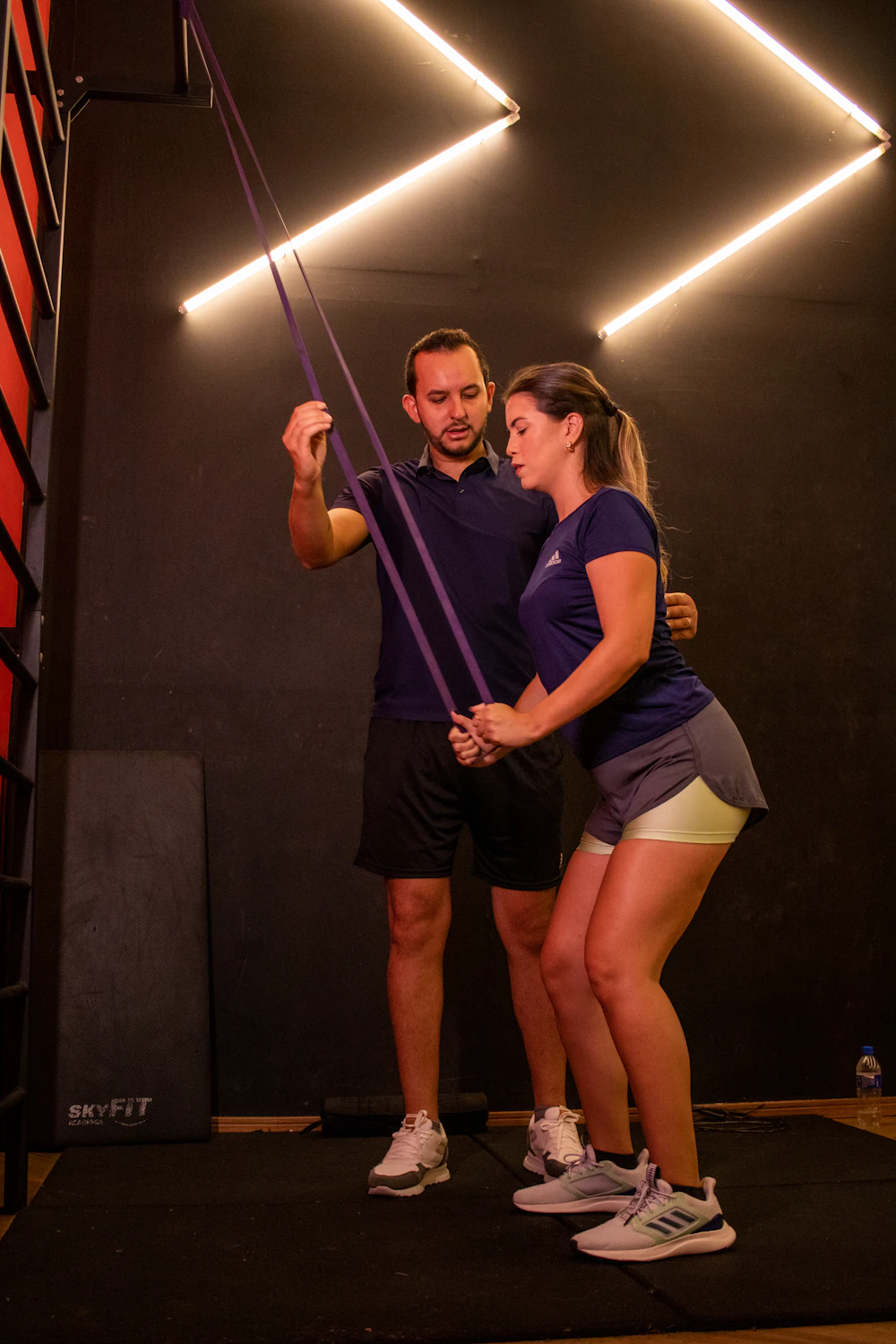 Trainerin unterstützt Sportlerin bei Übung mit Widerstandsband