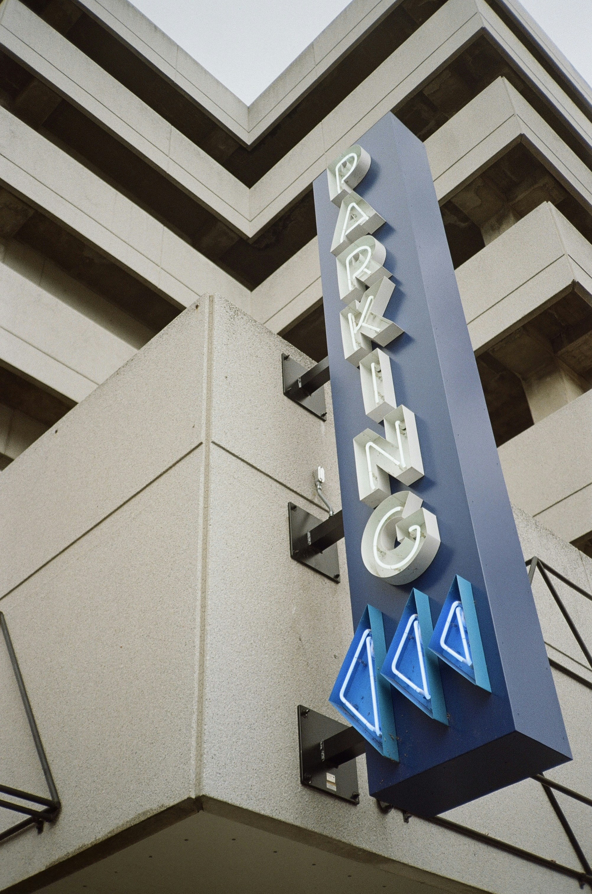 Blue parking sign with neon accents on building