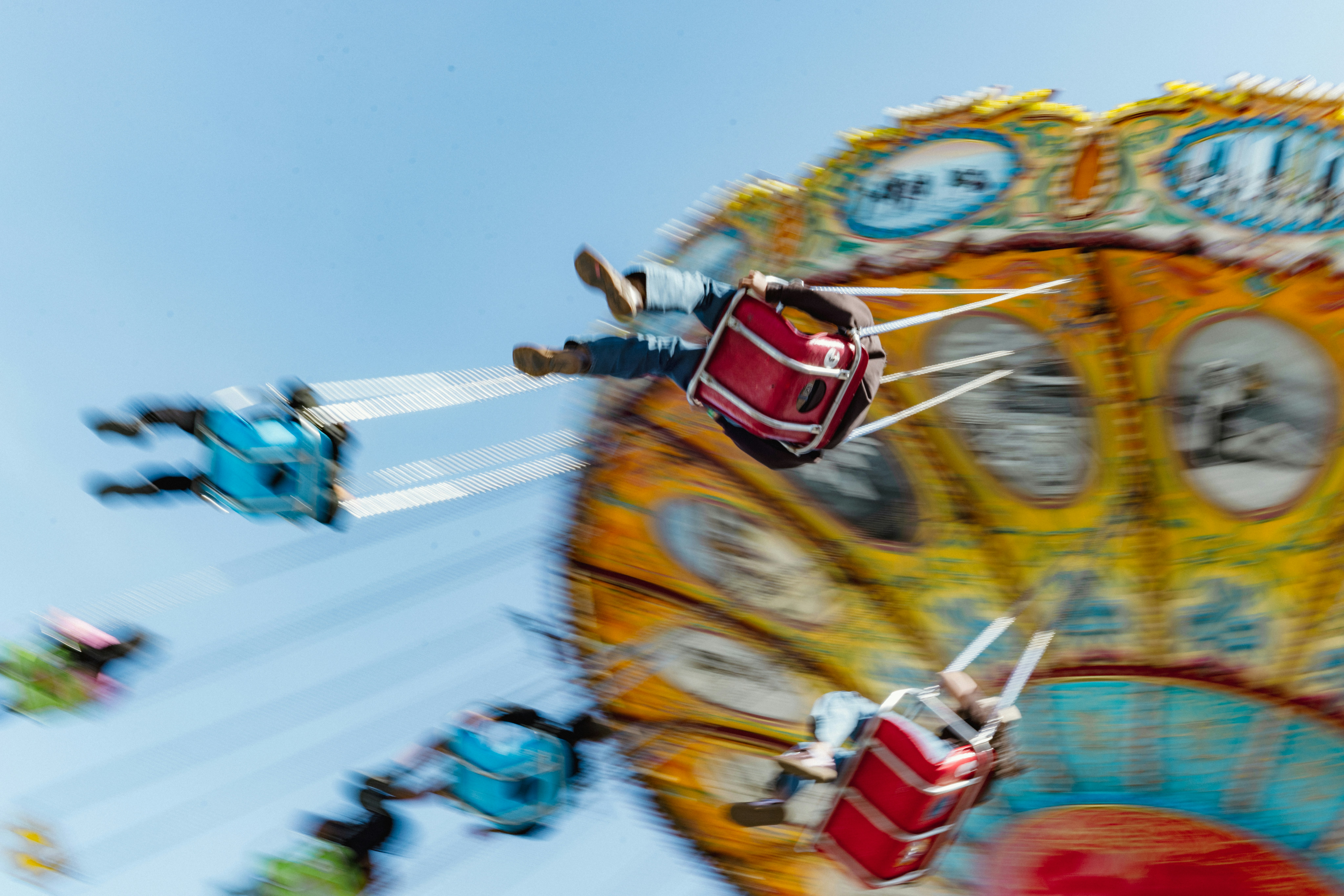 People on a spinning carnival ride under a clear sky