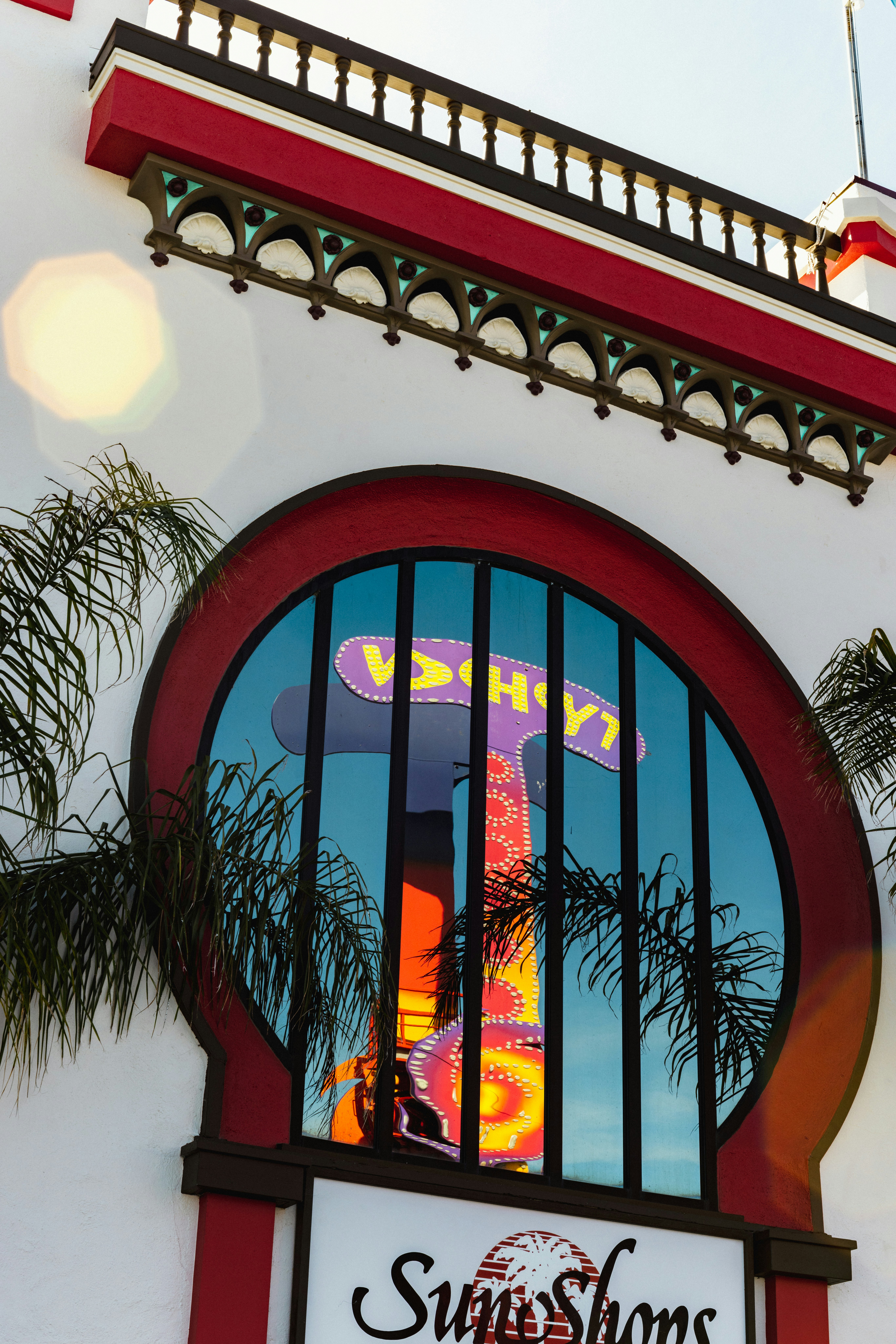 Neon sign reflected in a large circular window.