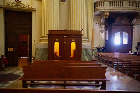 Wooden pews inside a grand church with tall columns.