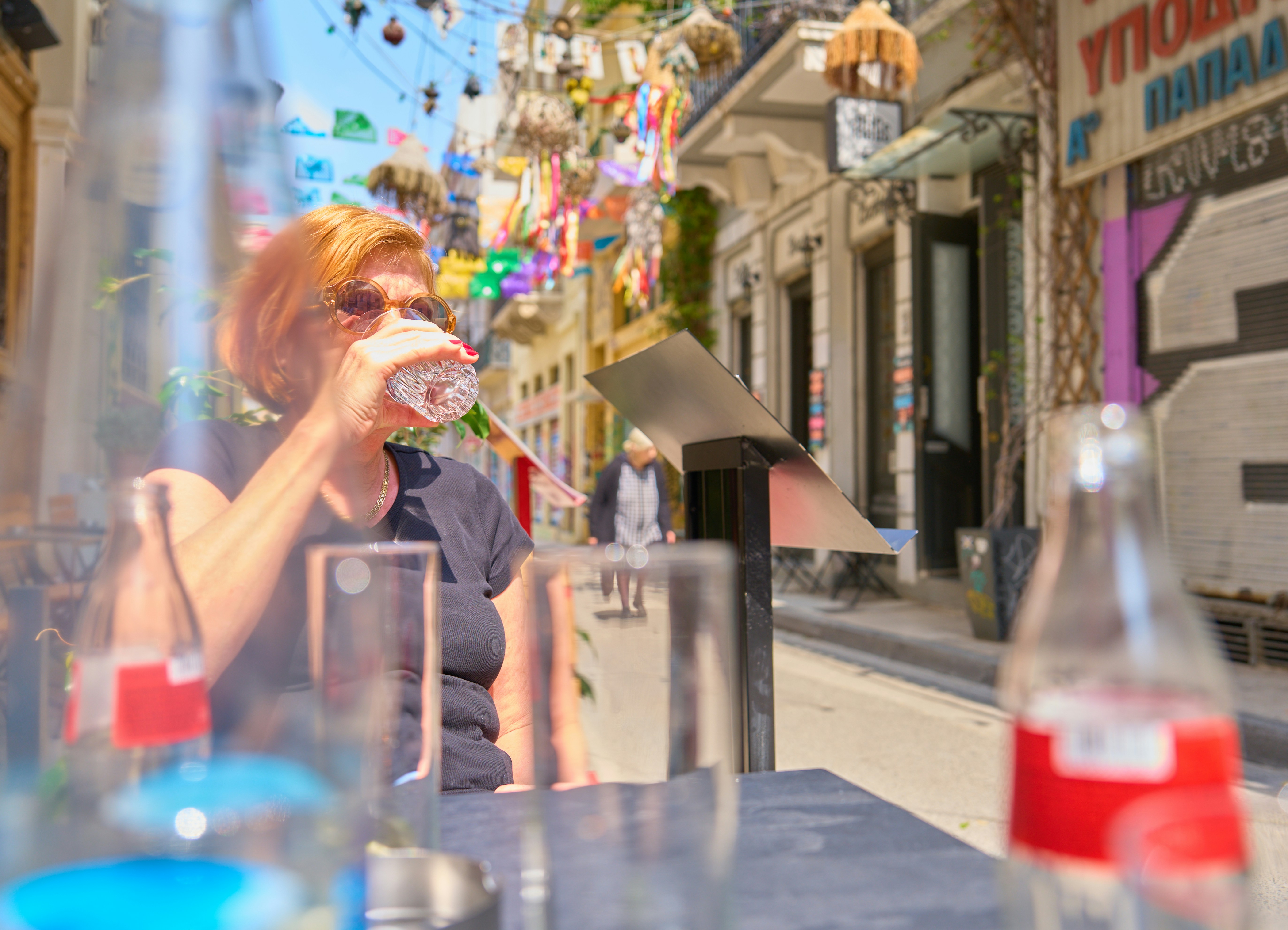 Donna che beve acqua in un caffè all'aperto