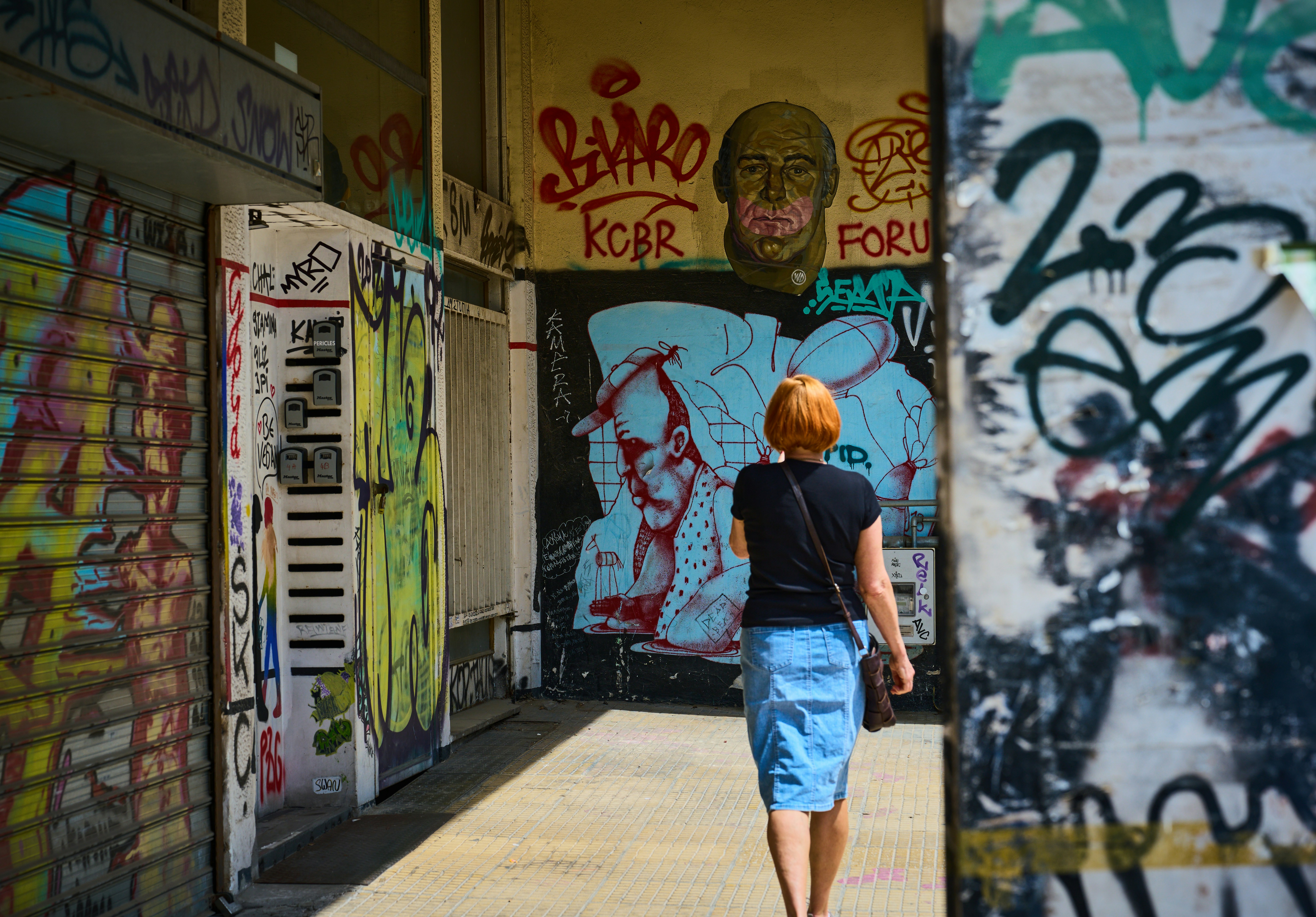 Una donna passa davanti ai muri coperti di graffiti