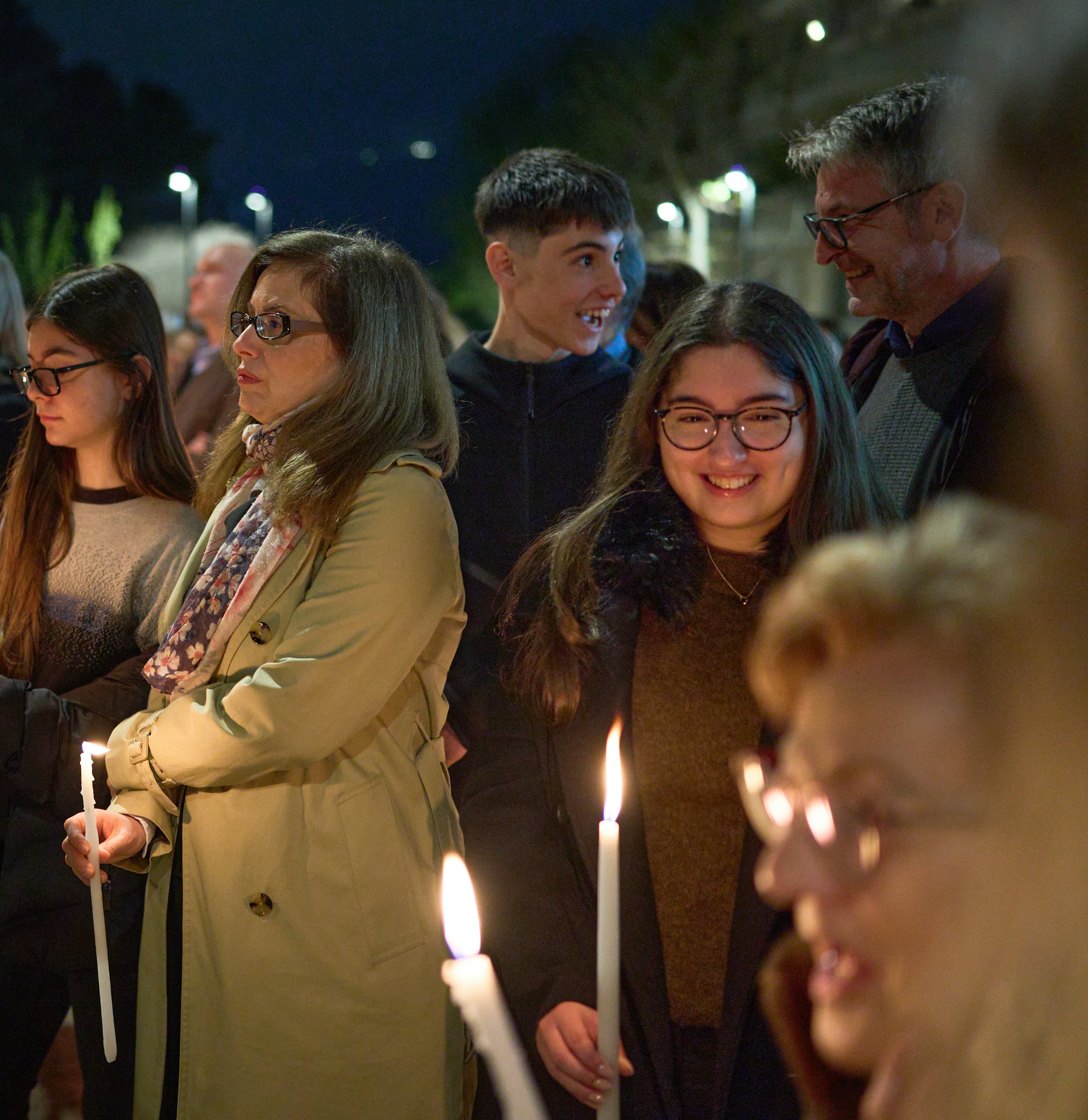 Persone che tengono candele di notte durante un evento