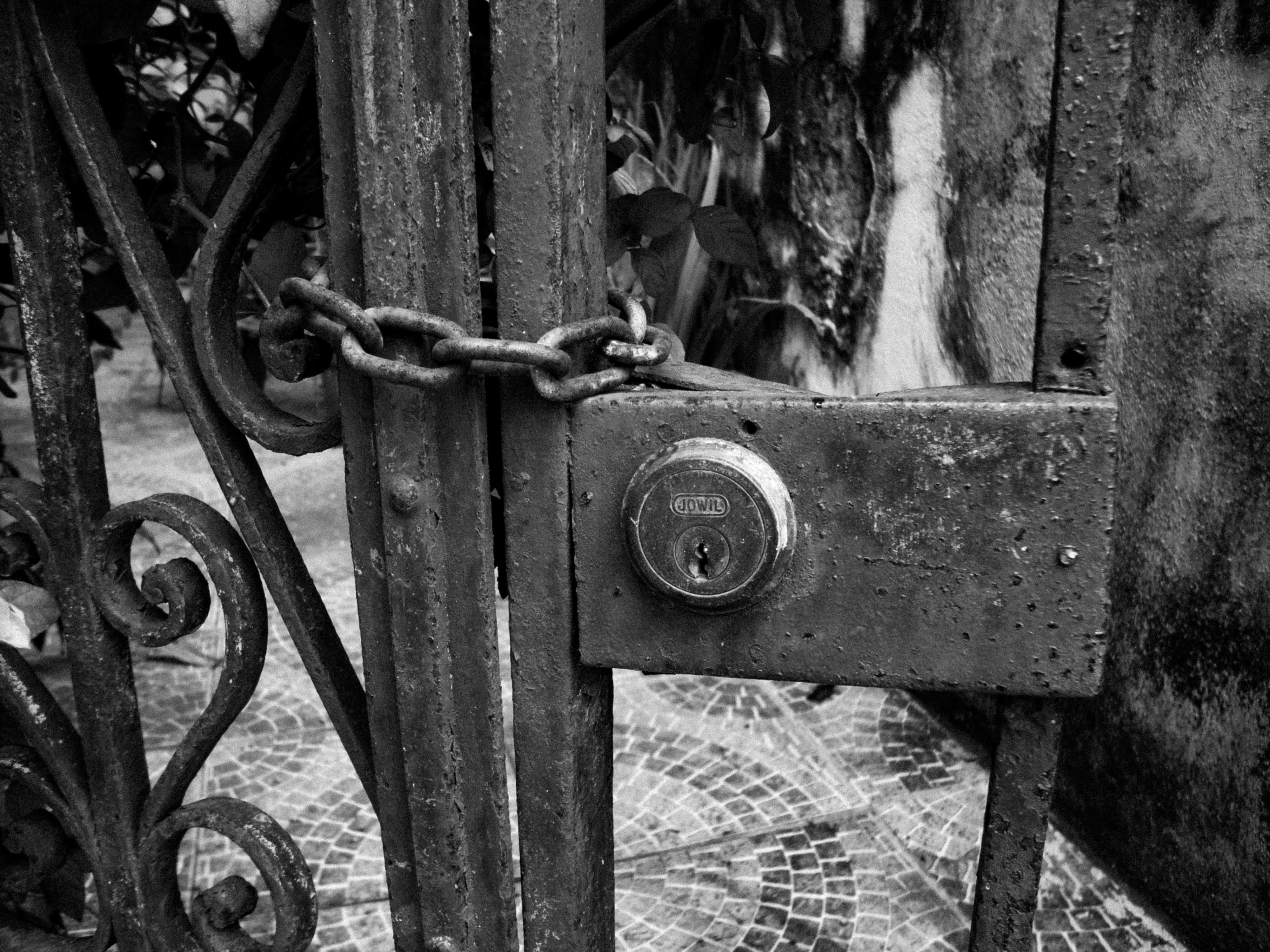 Rusty metal gate secured with a chain and lock.