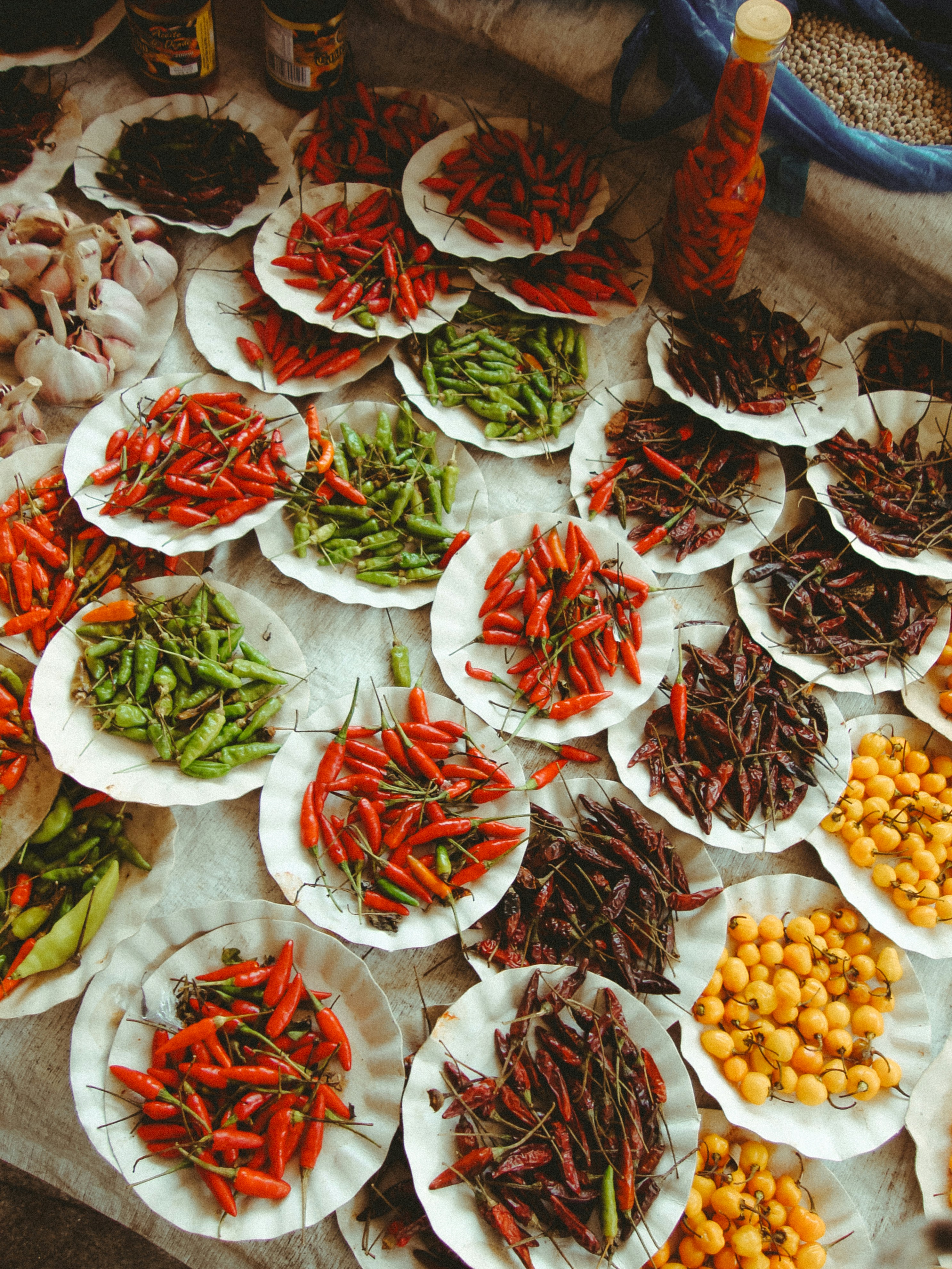 Plates of assorted chilies and small yellow fruits