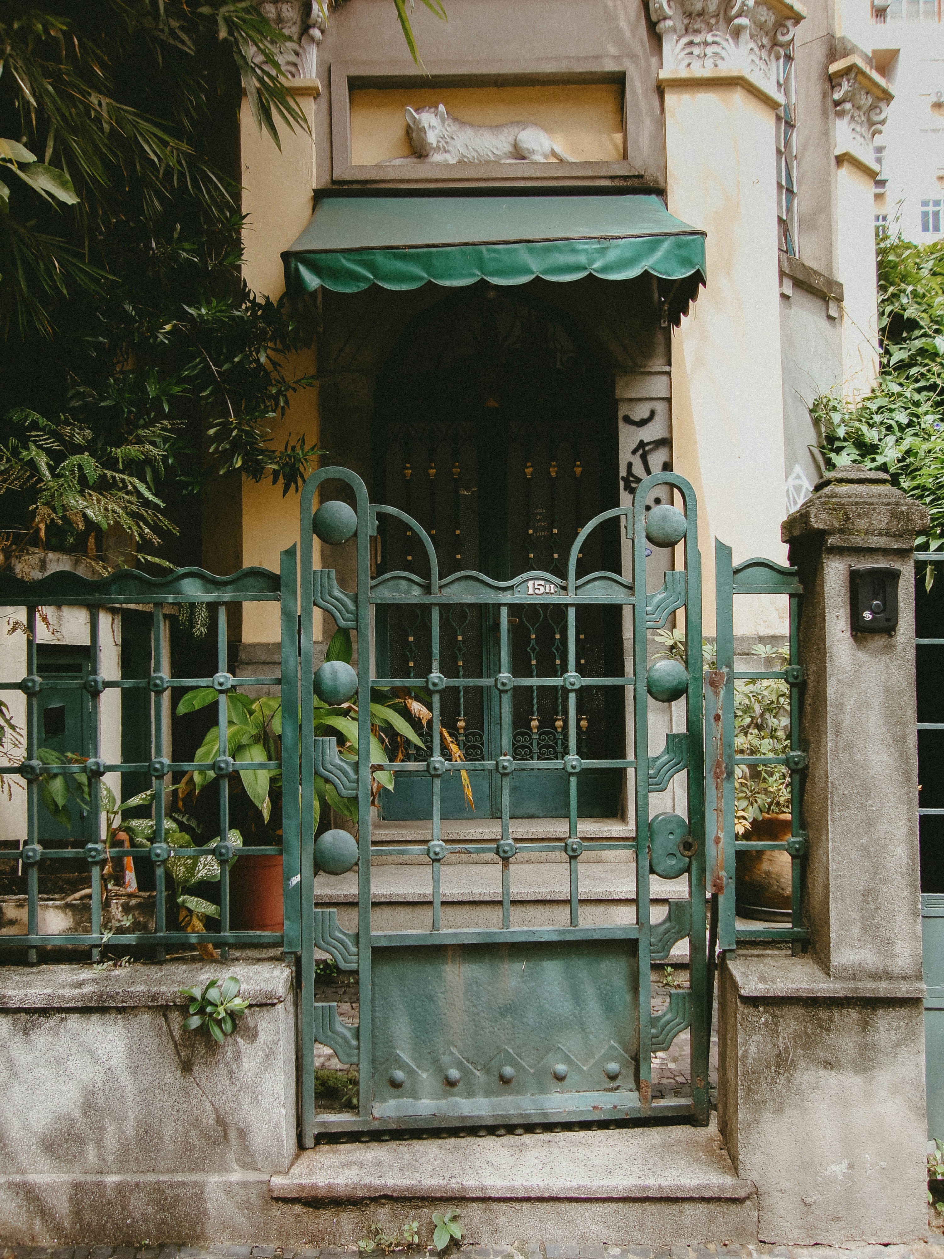 Ornate green gate in front of a charming house entrance