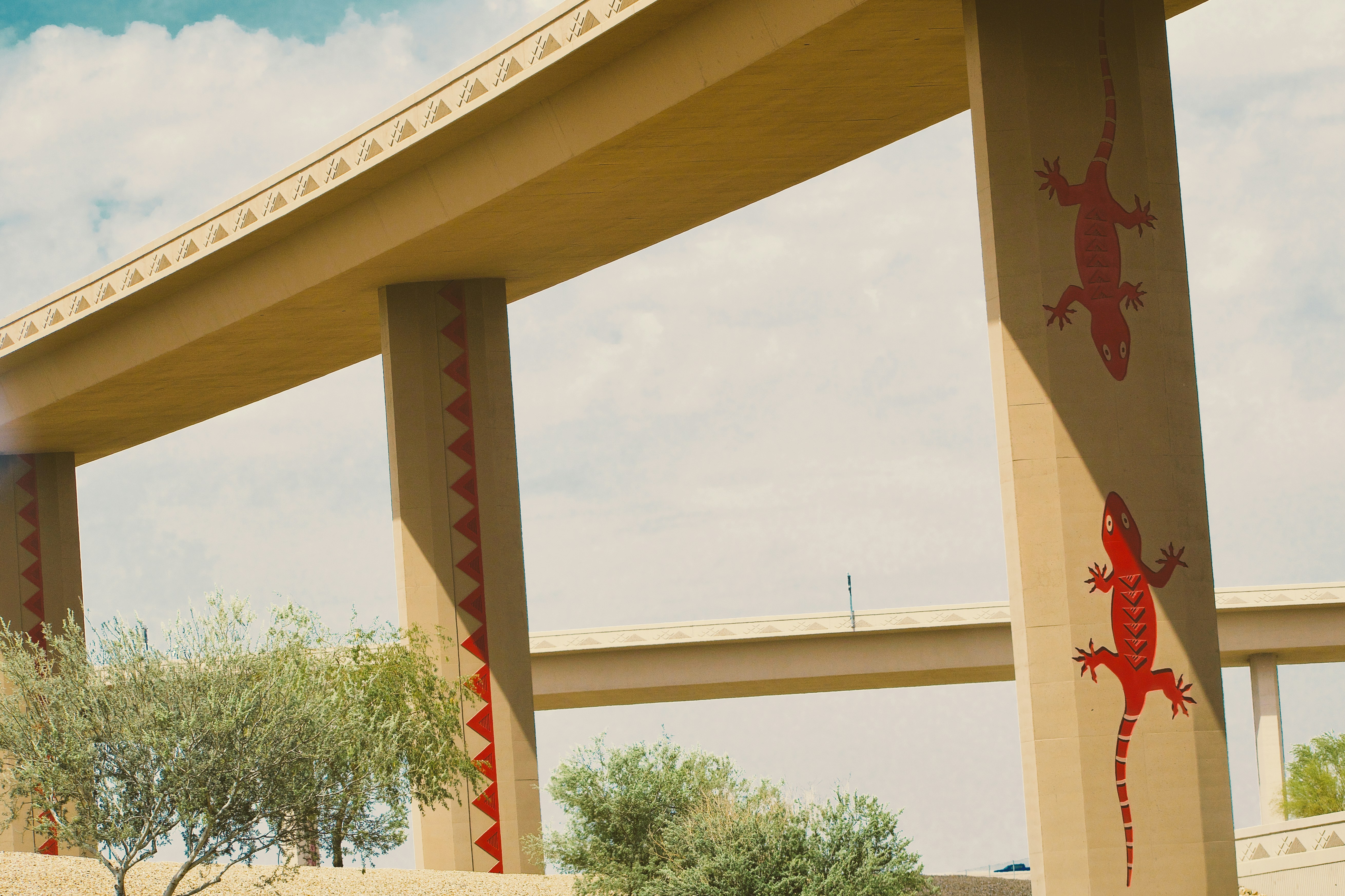 Betonbrückenpfeiler, verziert mit roter Echsenkunst.