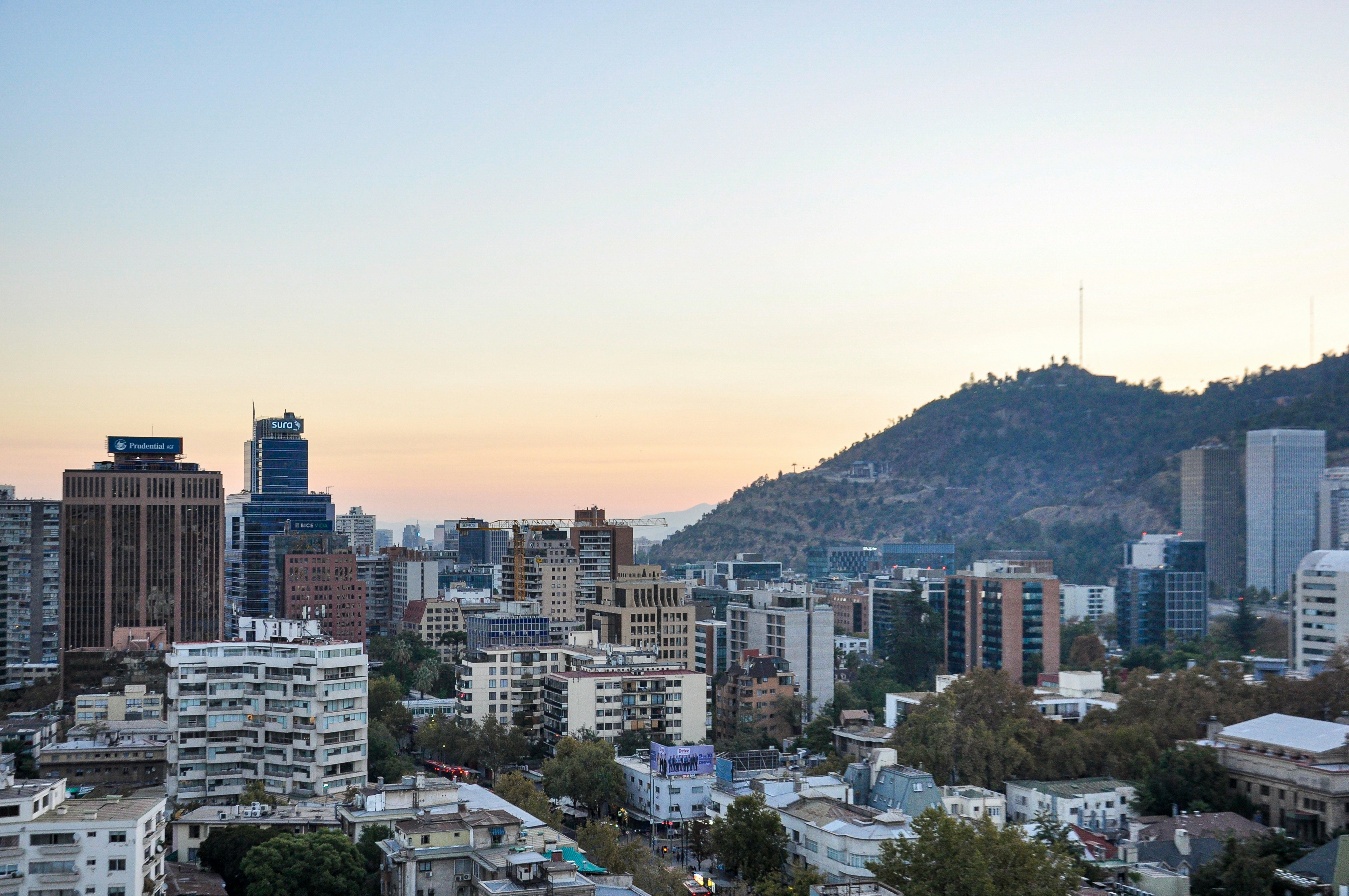 Horizonte urbano con edificios y una montaña al atardecer.