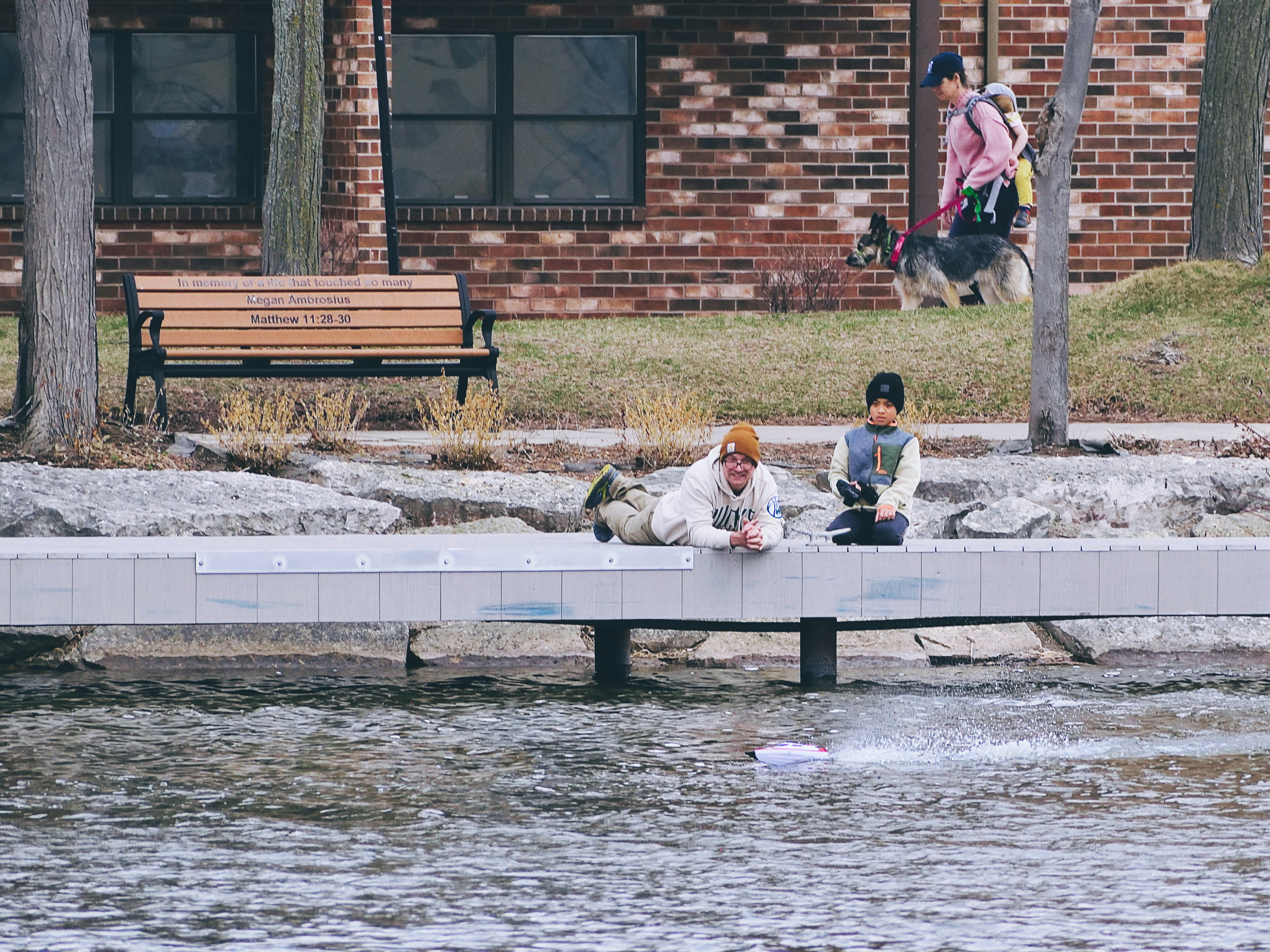 Zwei Kinder beobachten ein Spielzeugboot auf dem Wasser.