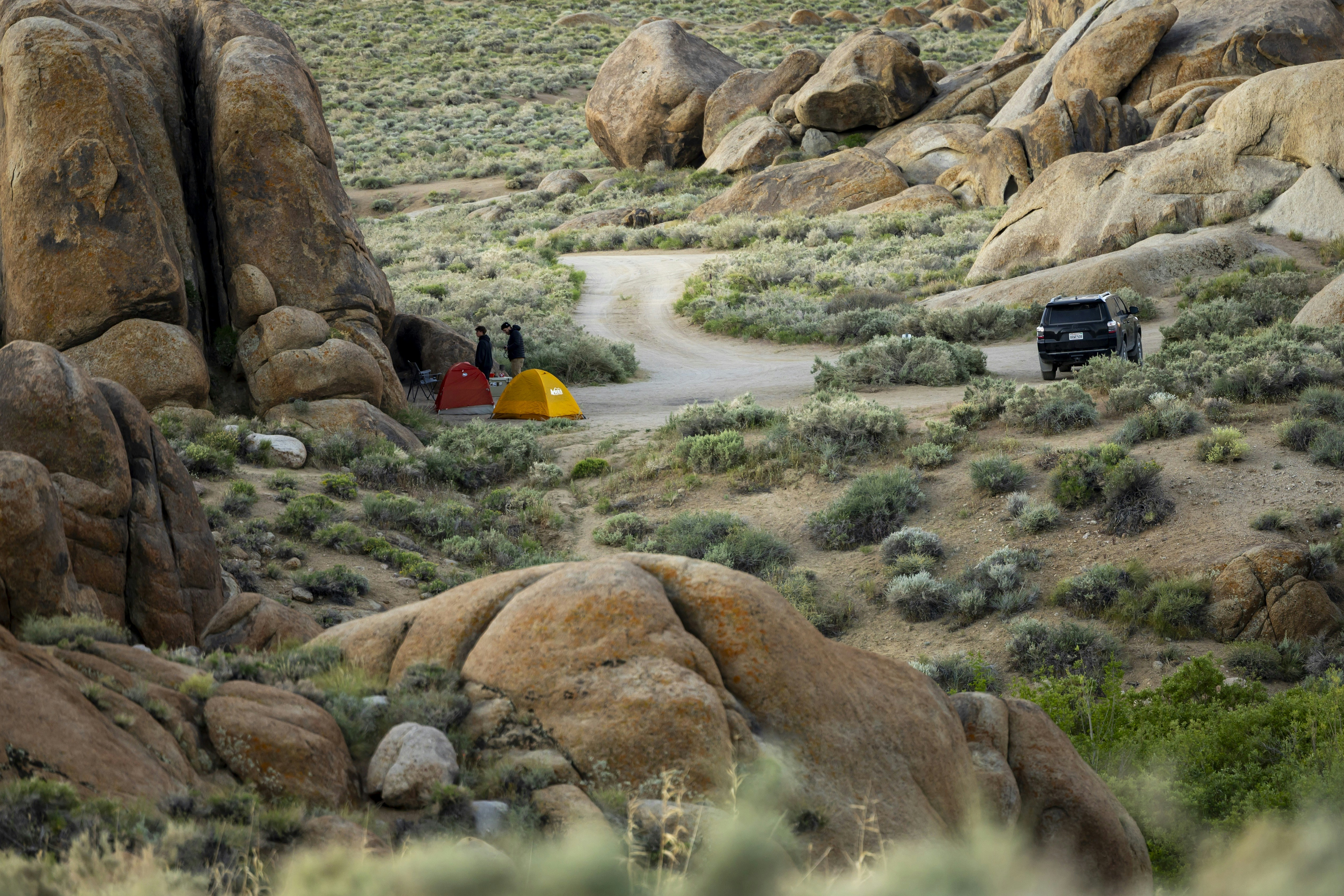 Tents and vehicle in a rocky, desert landscape.