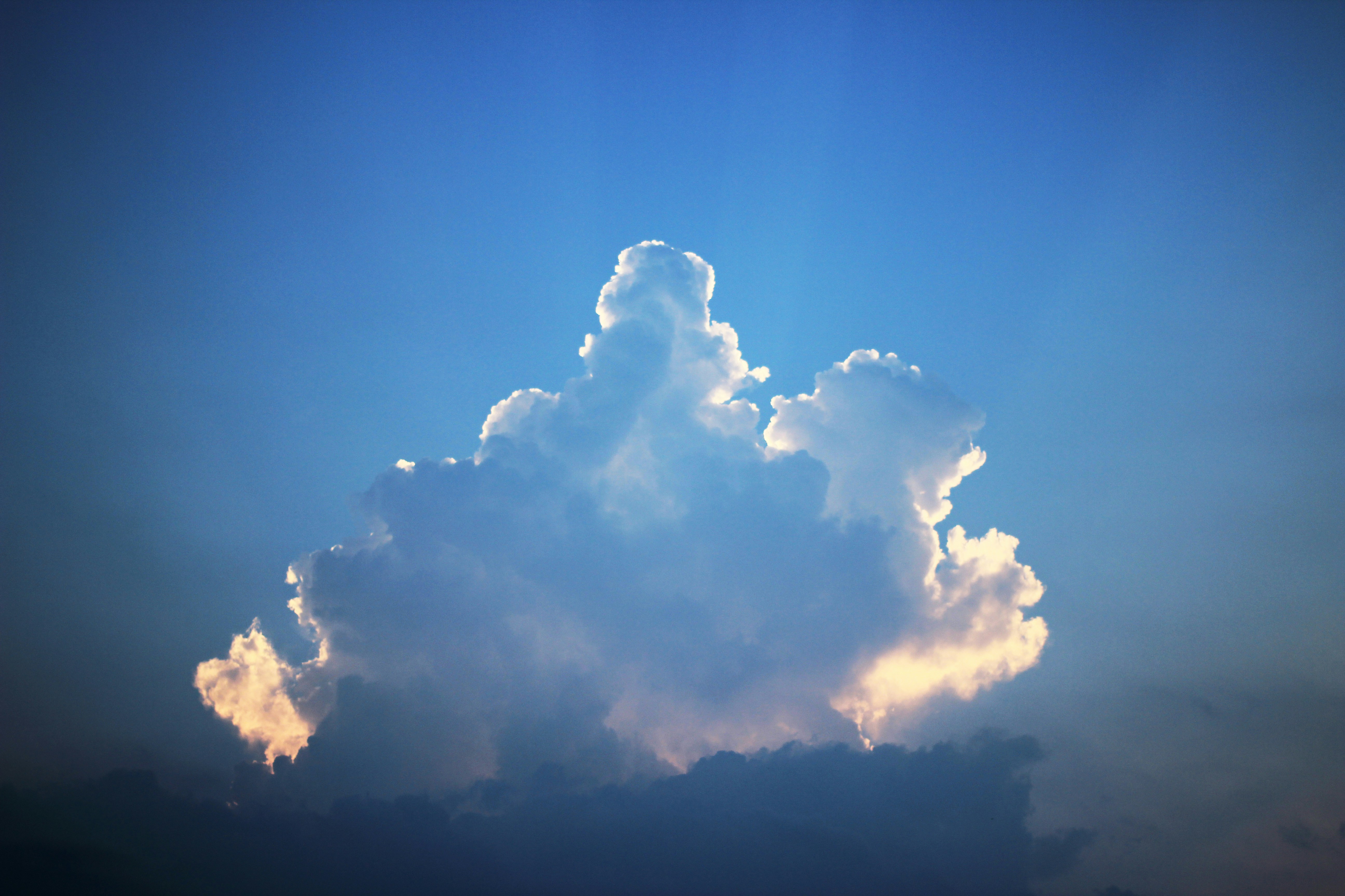 A single cloud illuminated by sunlight against a blue sky