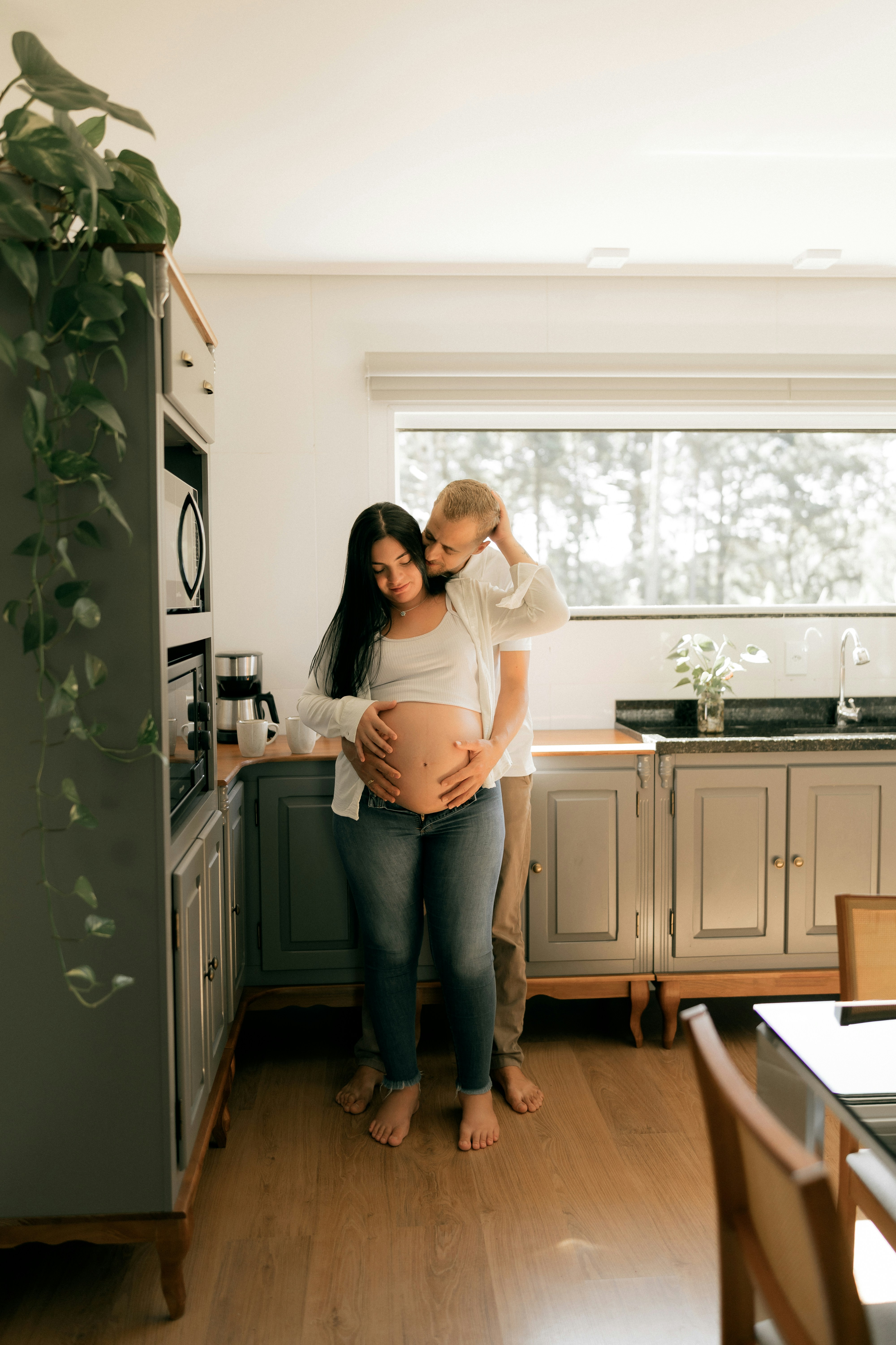 Una pareja embarazada abrazándose en una cocina.