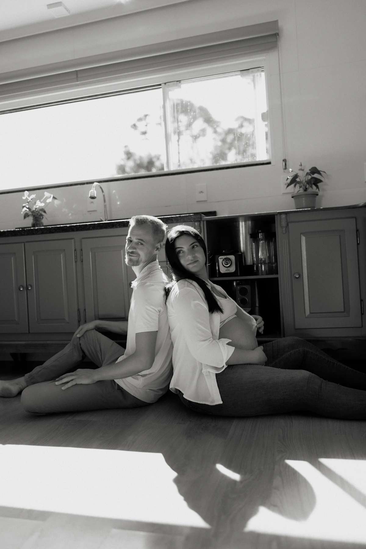 A couple sitting back to back on a floor at home