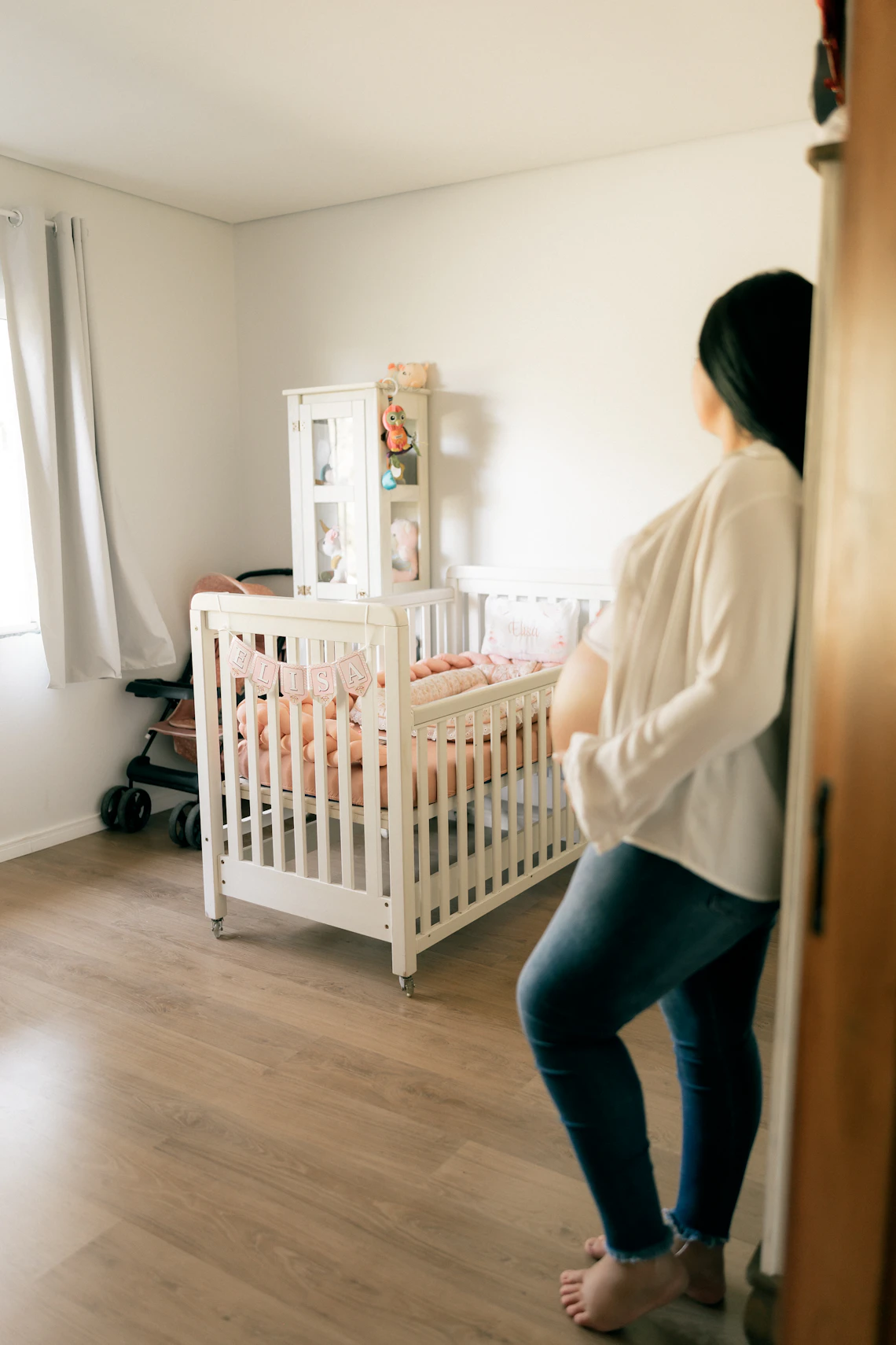 Expectant mother standing beside a prepared nursery crib