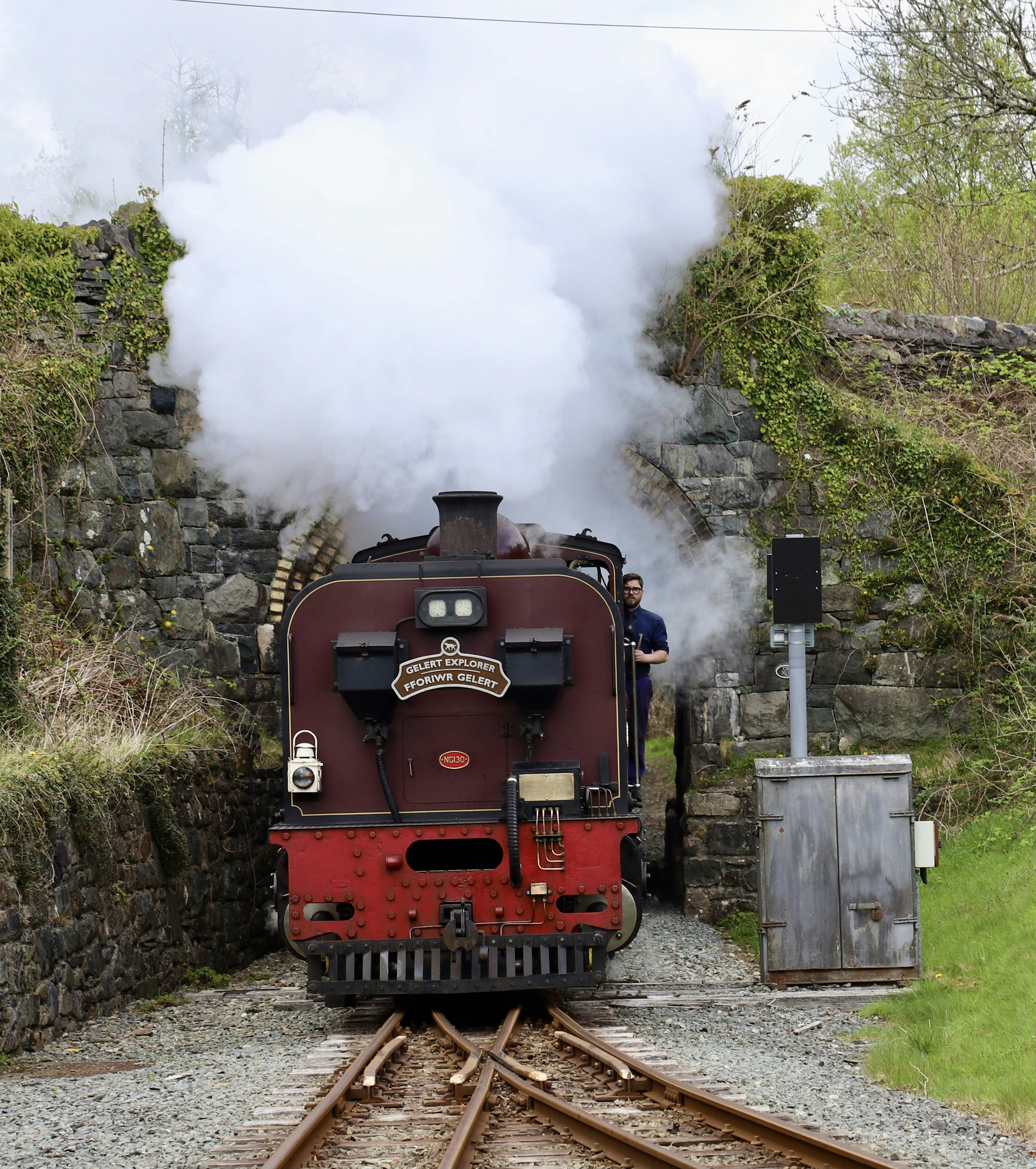 Un train à vapeur ancien sort d’un tunnel en pierre.