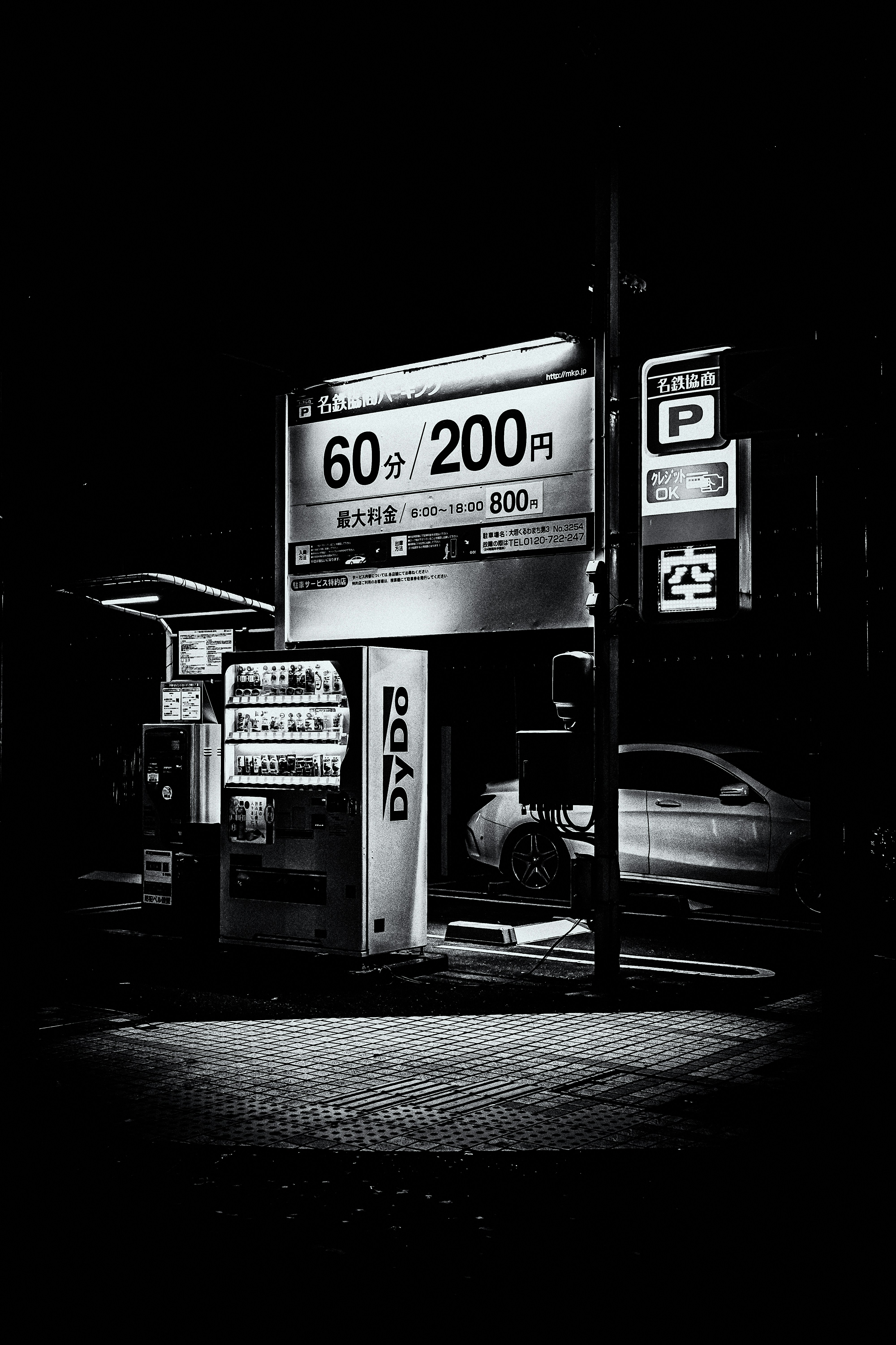 Pemandangan malam dengan mesin penjual otomatis dan mobil yang diparkir