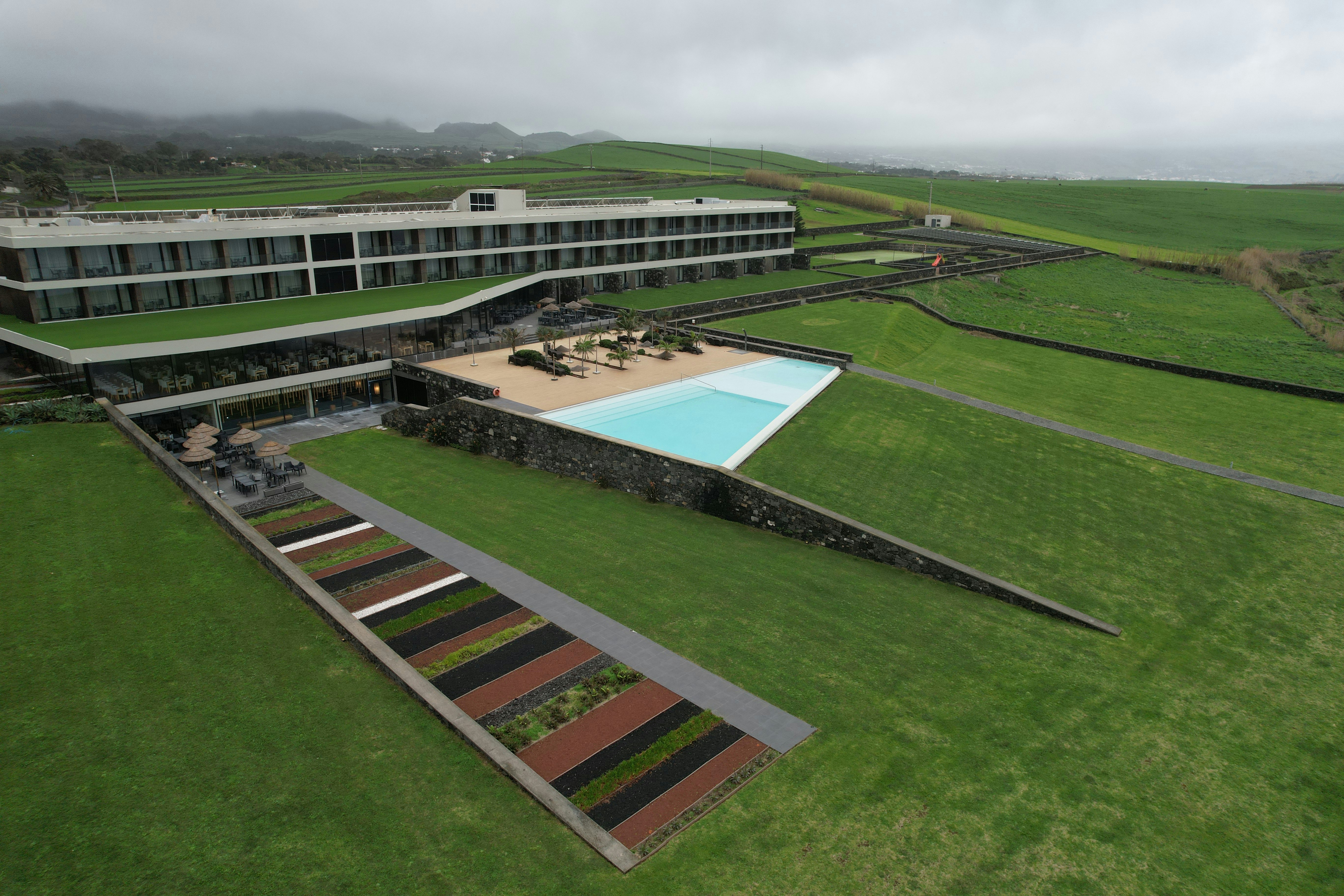 Modern hotel with pool on green grassy hillside