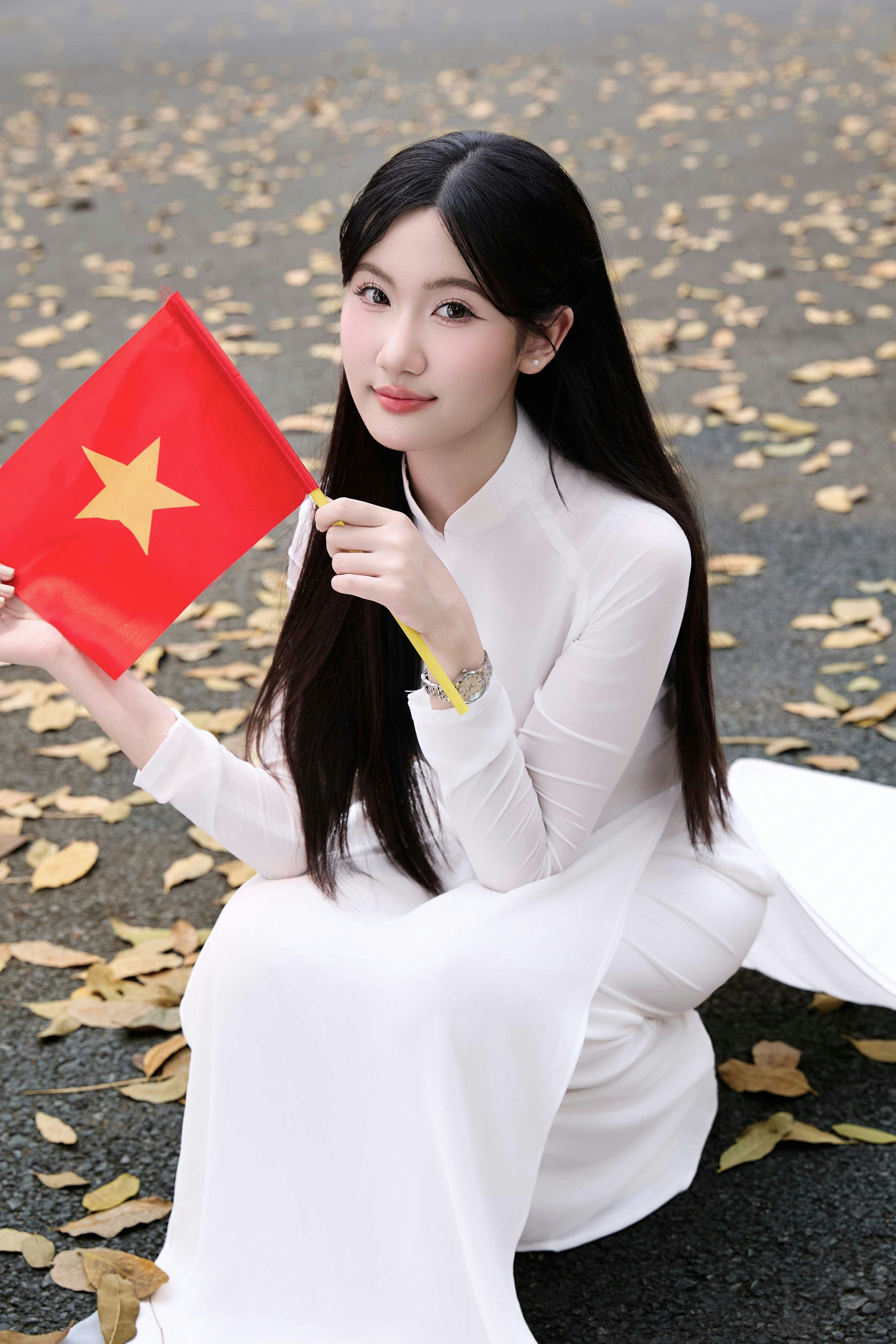 Jovem mulher de branco ao dai segurando a bandeira vietnamita
