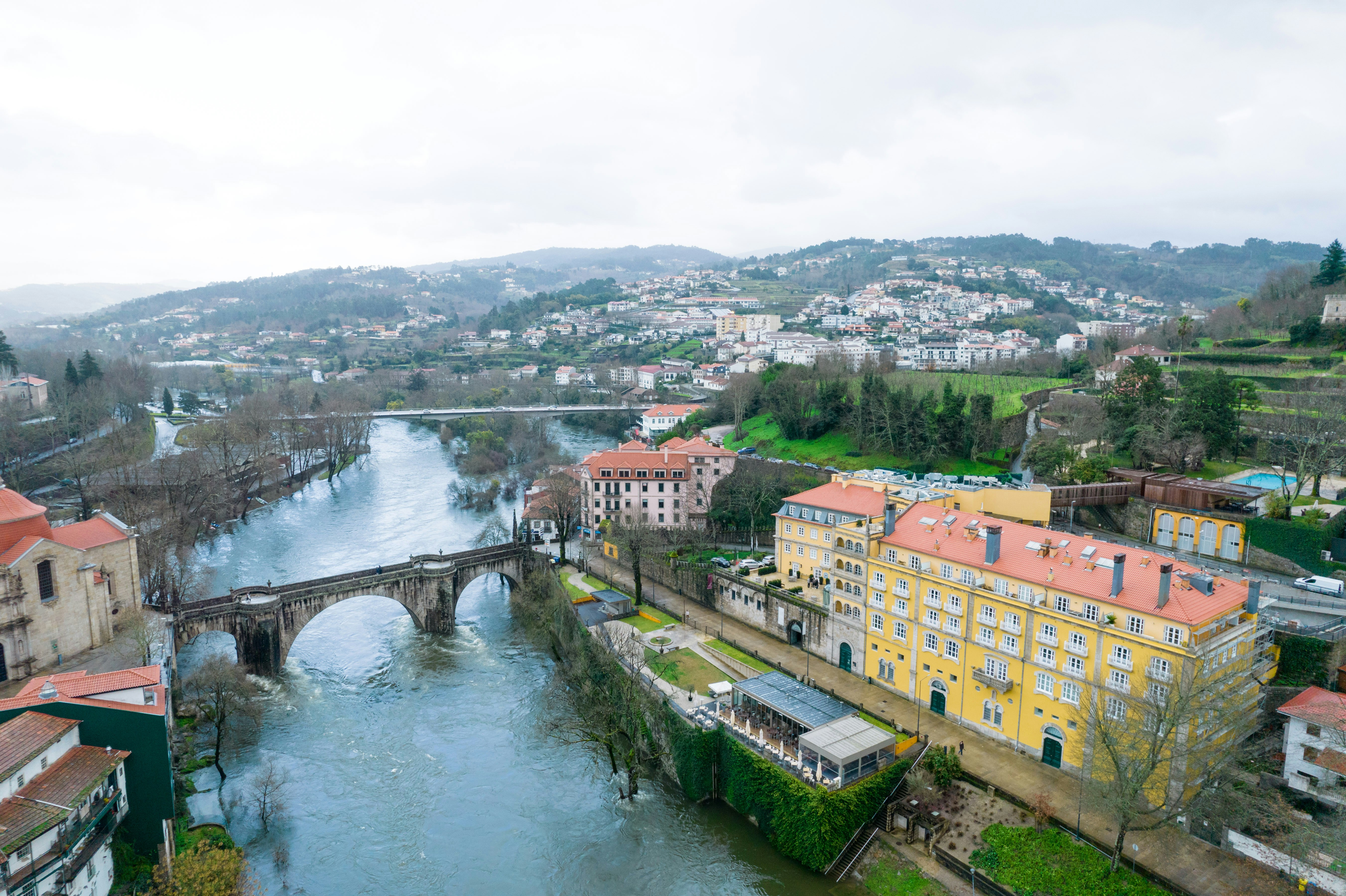 River flows through a historic european town with bridge.