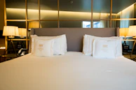 A neatly made bed with white pillows and lamps.