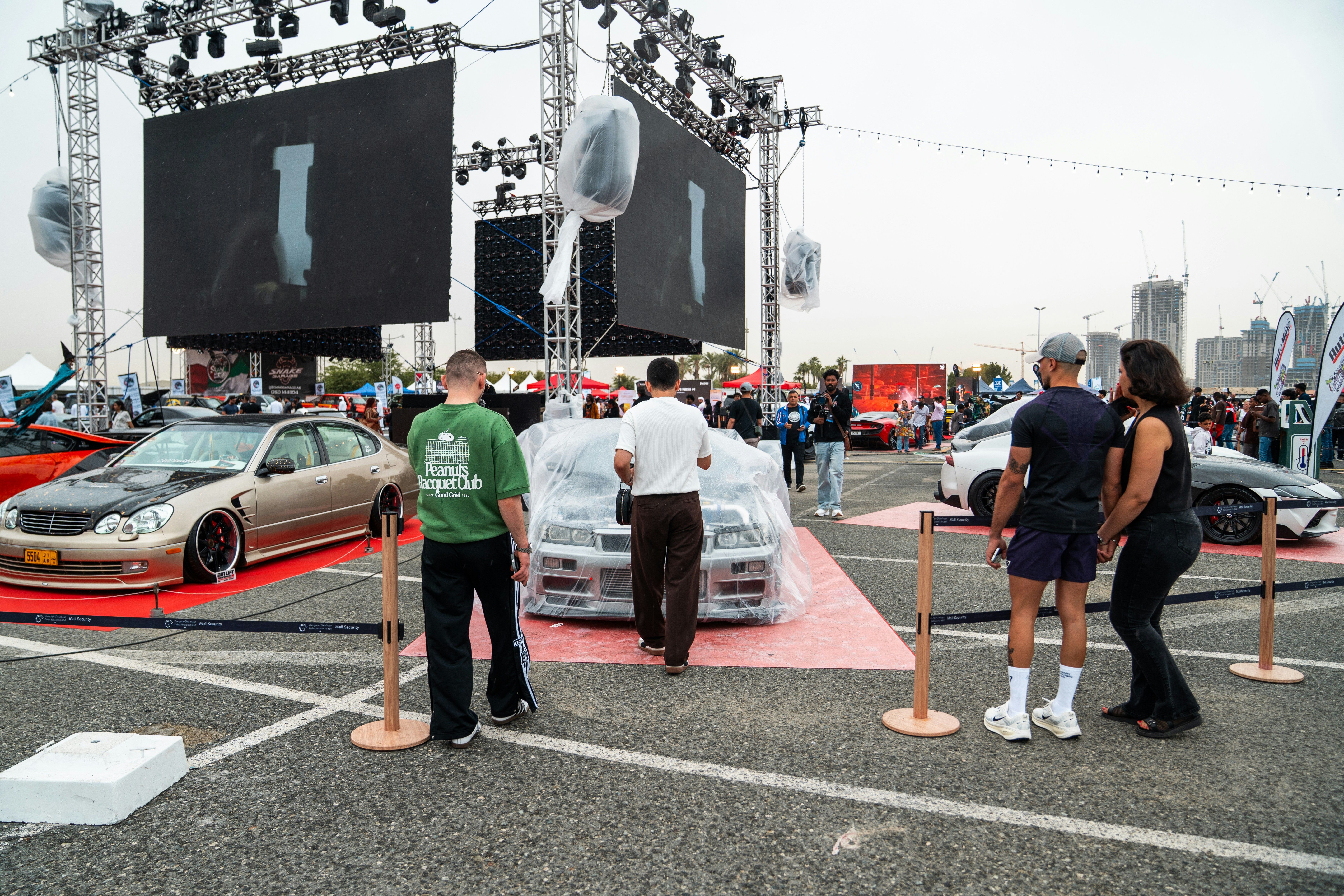 People admire custom cars at an outdoor event.