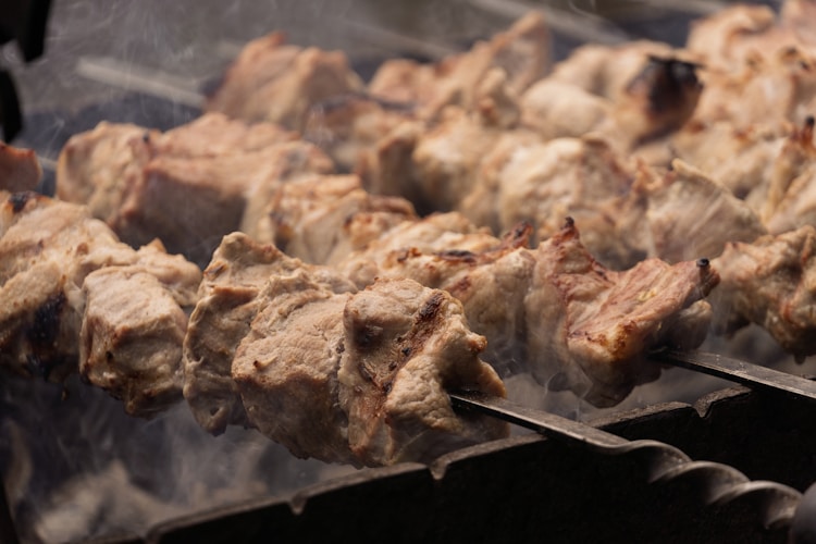 Grilled meat sizzling over an open fire at a food truck