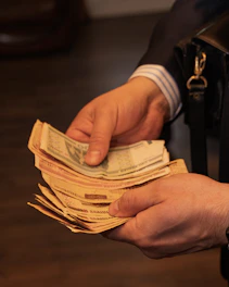 Hands holding a stack of assorted banknotes